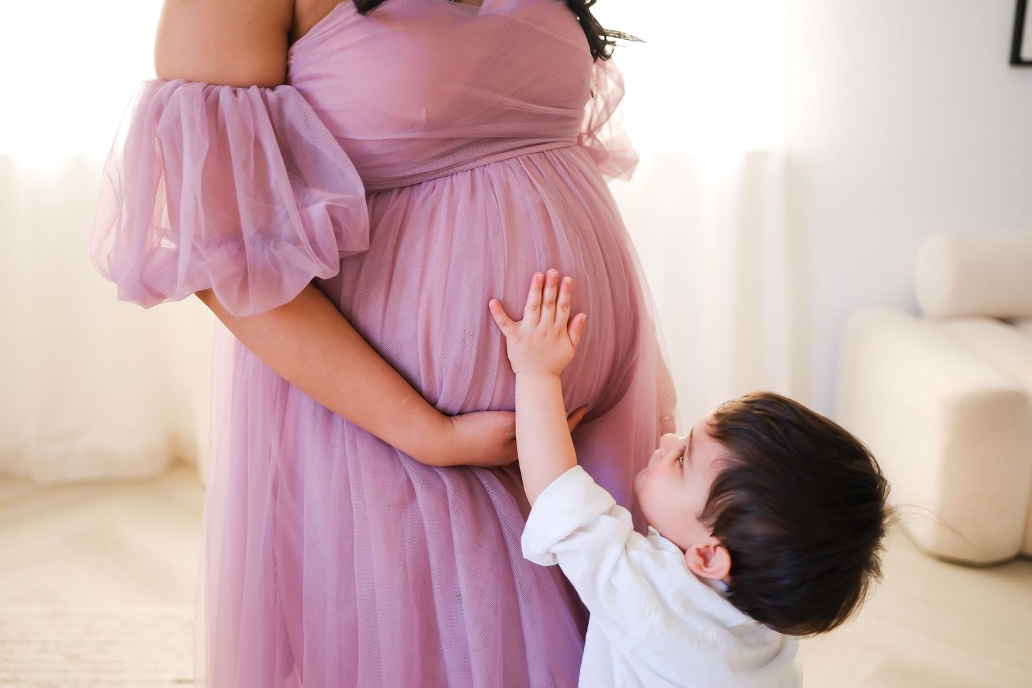 Small child reaches up to touch flowing pink maternity dress. Toronto, photographer, majestystudios, greater toronto area, photoshoot,family