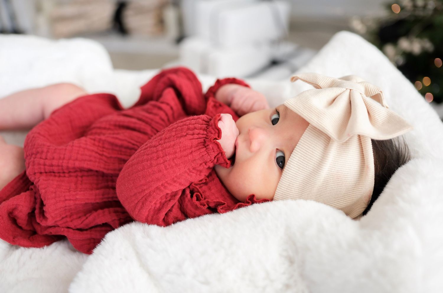 A collection of cozy red and white knit blankets and accessories arranged in a soft, dreamy holiday setting.