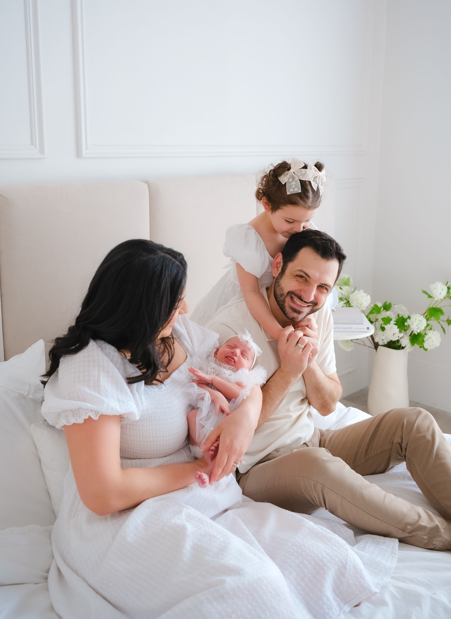 A happy family sharing joyful moments together on a white couch with green plants in the background.