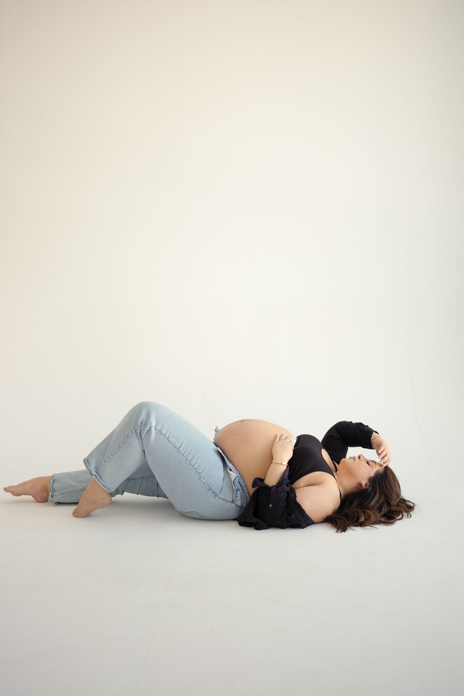A series of minimalist photographs showing a person lying on their side against a white background in different poses.