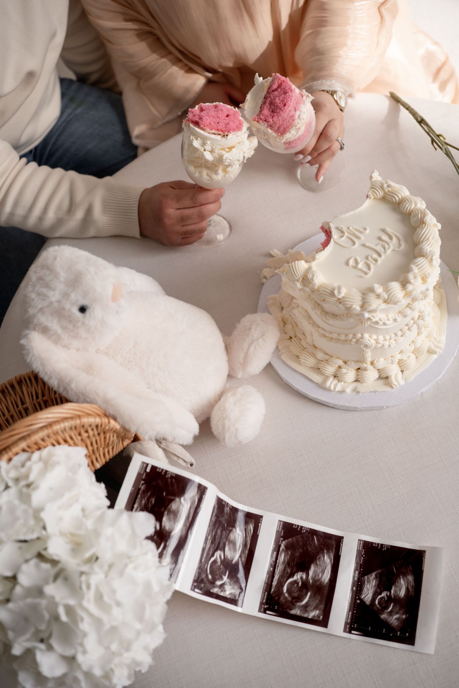 A series of ultrasound photos displayed on a table with white plush toys and decorative items.