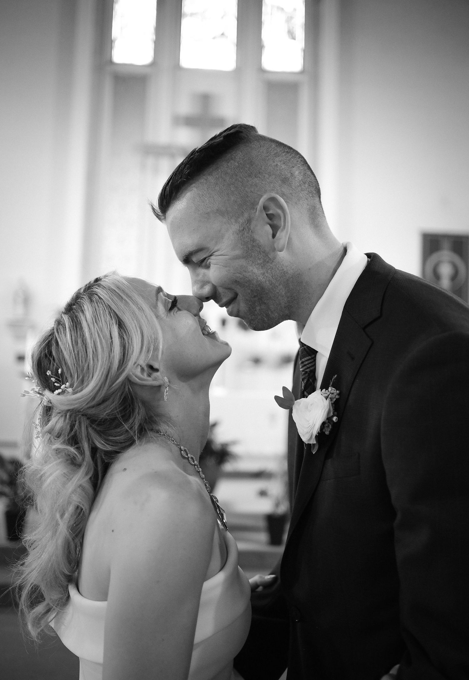 A tender black and white wedding moment captured in a church as a couple shares an intimate close embrace.