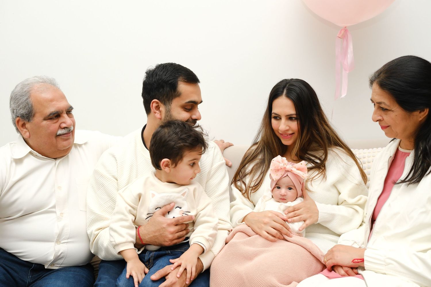 Family with newborn gathering with balloon in white and cream outfits. Toronto, photographer, majestystudios, greater toronto area