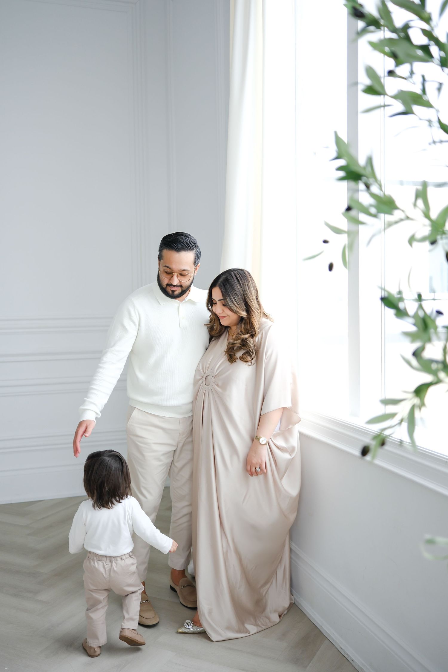 Family in cream outfits sharing tender moment near window. Toronto, photographer, majestystudios, greater toronto area, portrait, couple