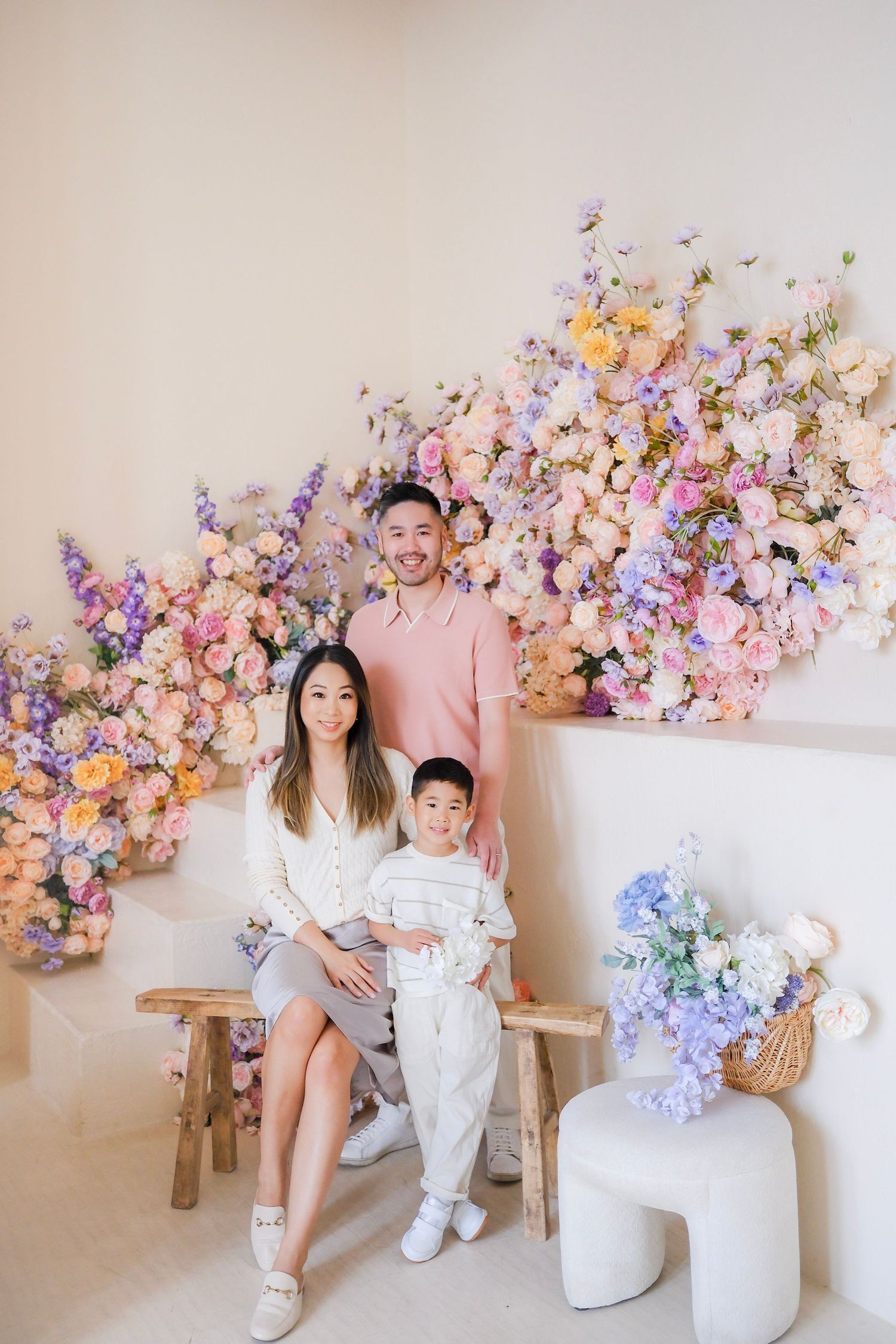 Beautiful floral arrangement with pink, purple and peach blooms decorates a family photo session against a neutral backdrop.