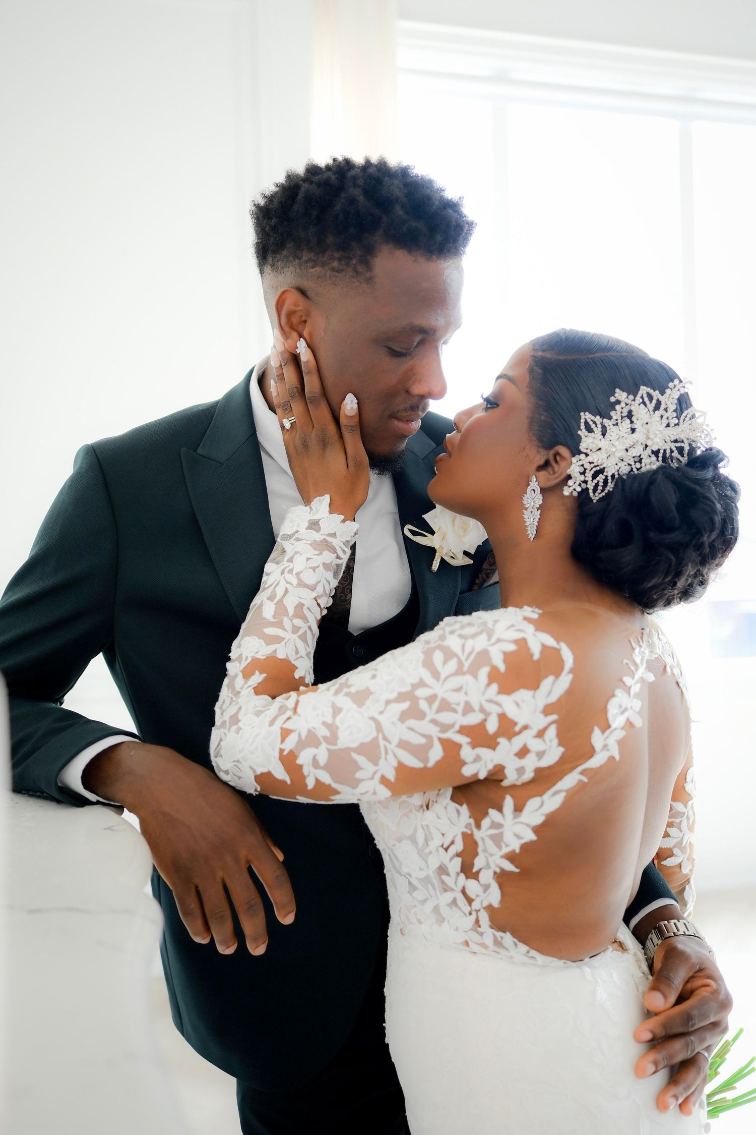 A romantic wedding moment with couple in elegant attire, bride wearing lace dress with delicate crown and groom in dark suit.