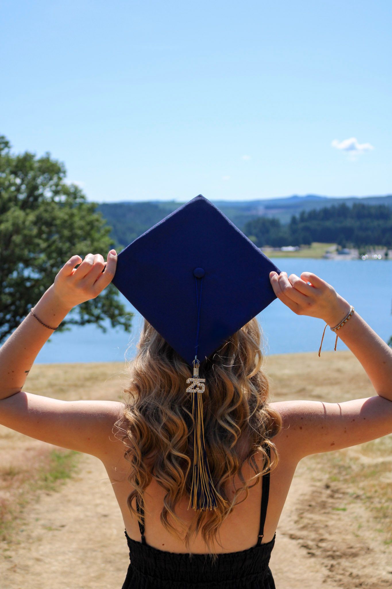 senior holding grad cap looking out at lake