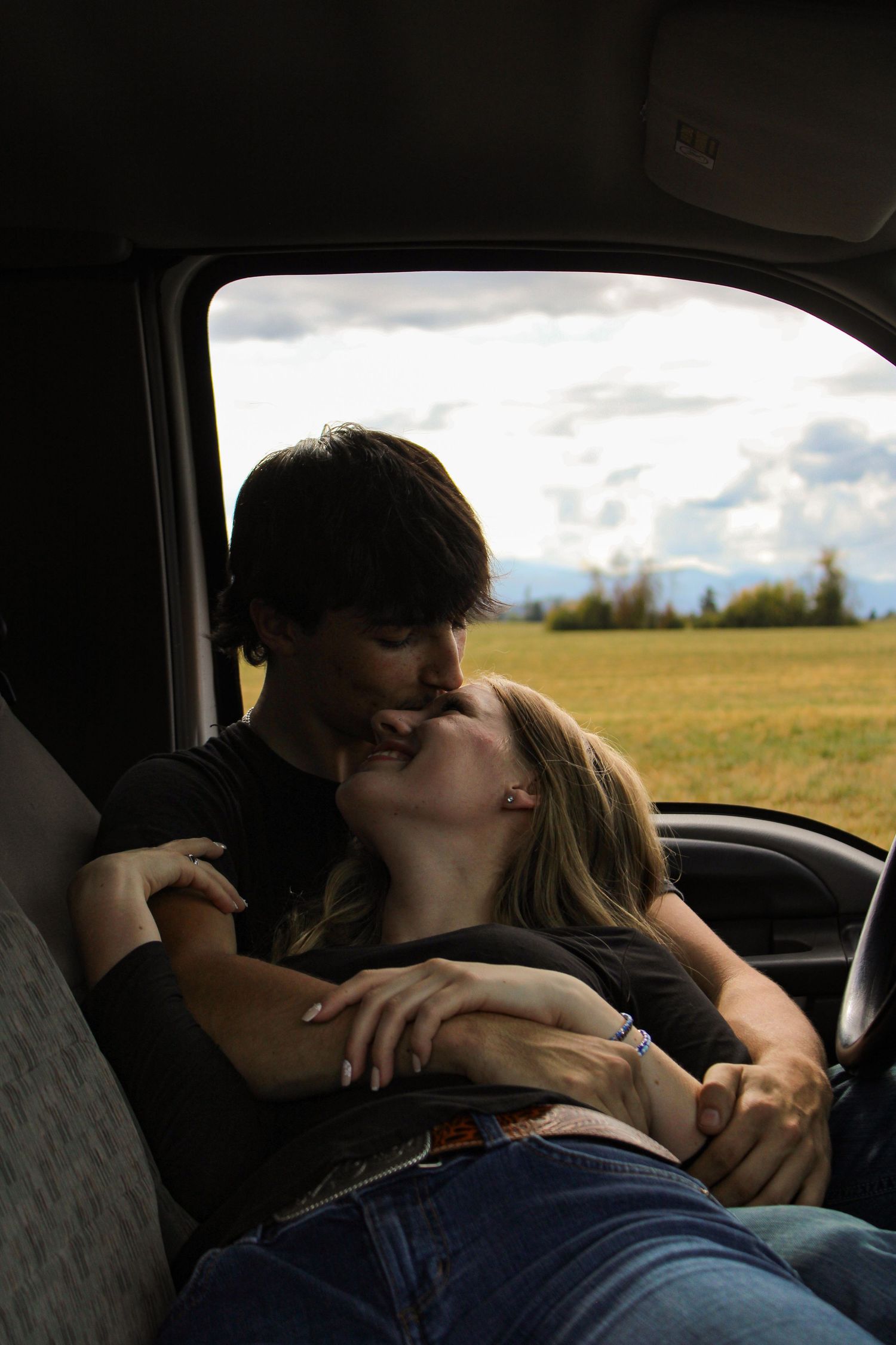 boyfriend kissing girlfriend's head, girlfriend laying against boyfriend's chest/lap