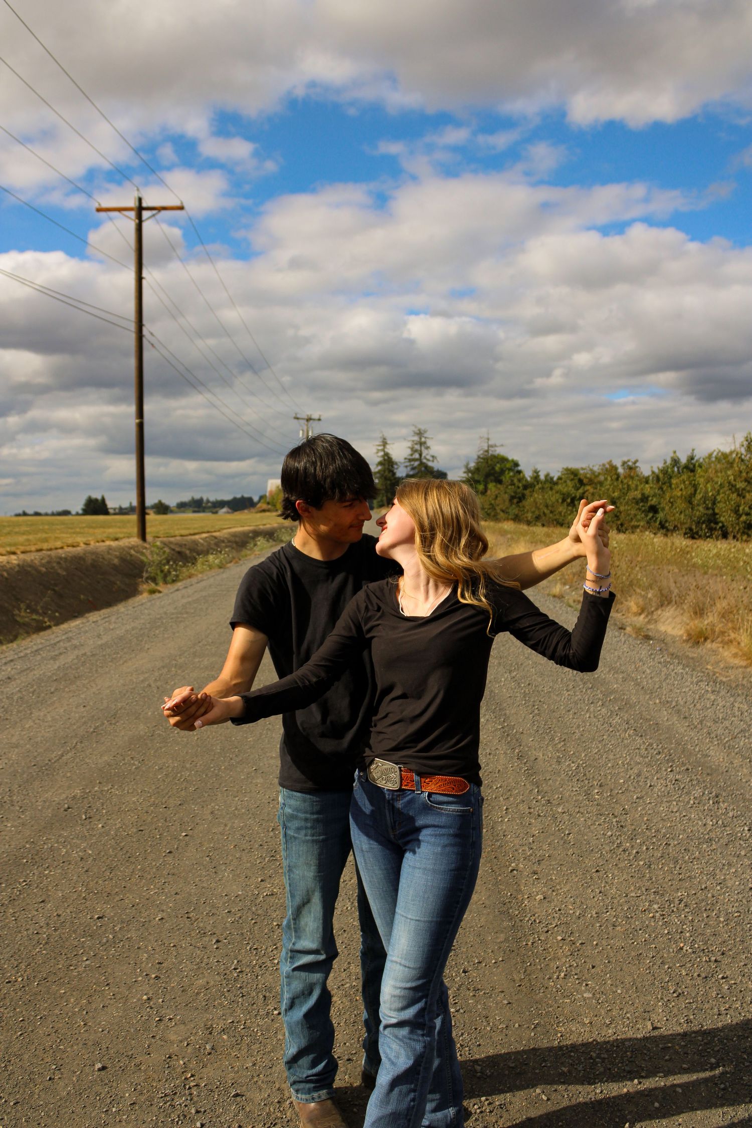 boyfriend and girlfriend standing on gravel road