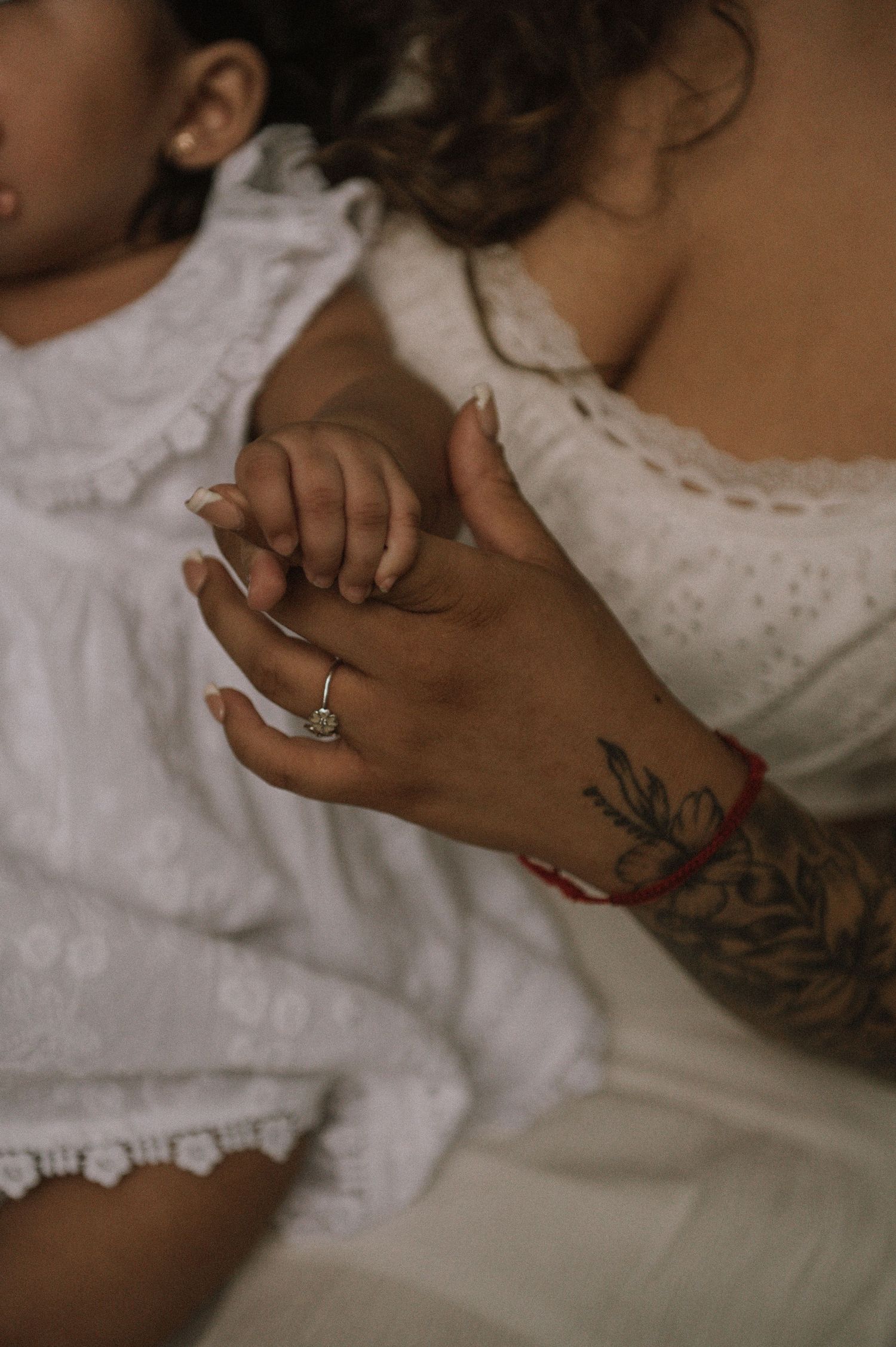 A close-up of two hands holding together, one wearing a diamond ring and the other adorned with a tattoo.