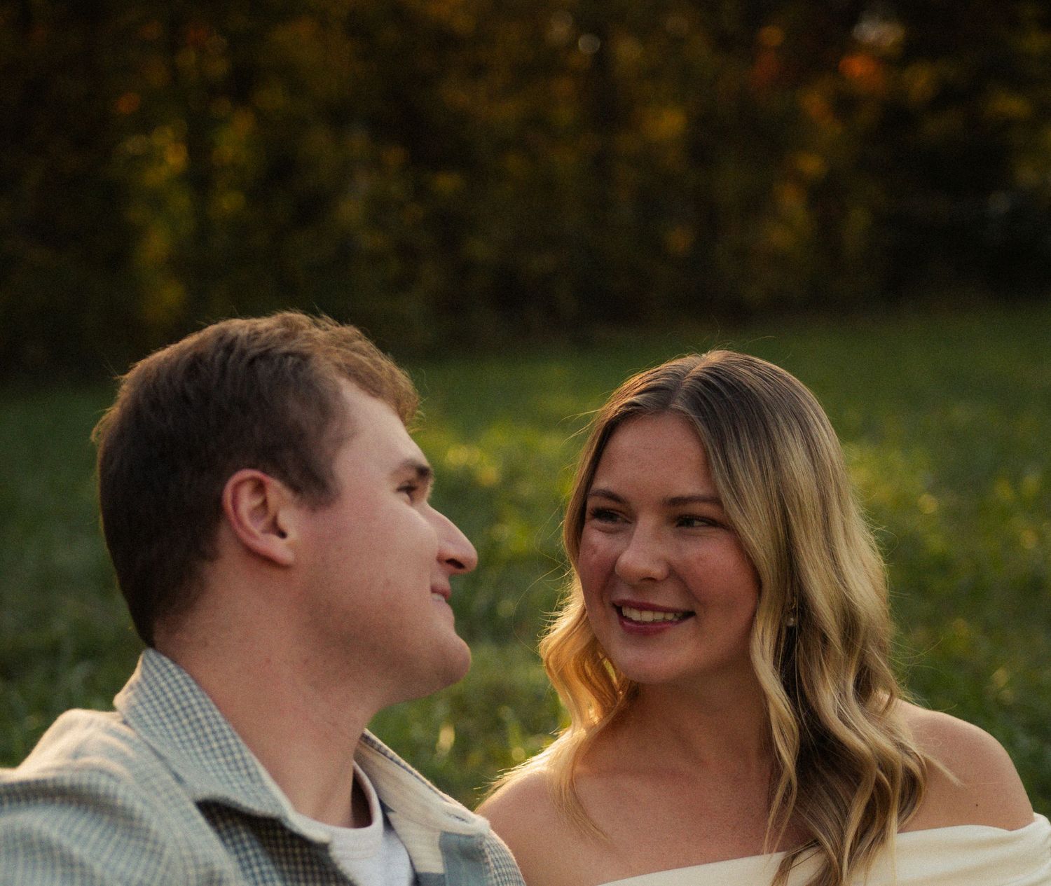 Young couple gazing at each other lovingly outdoors in a golden evening light setting.