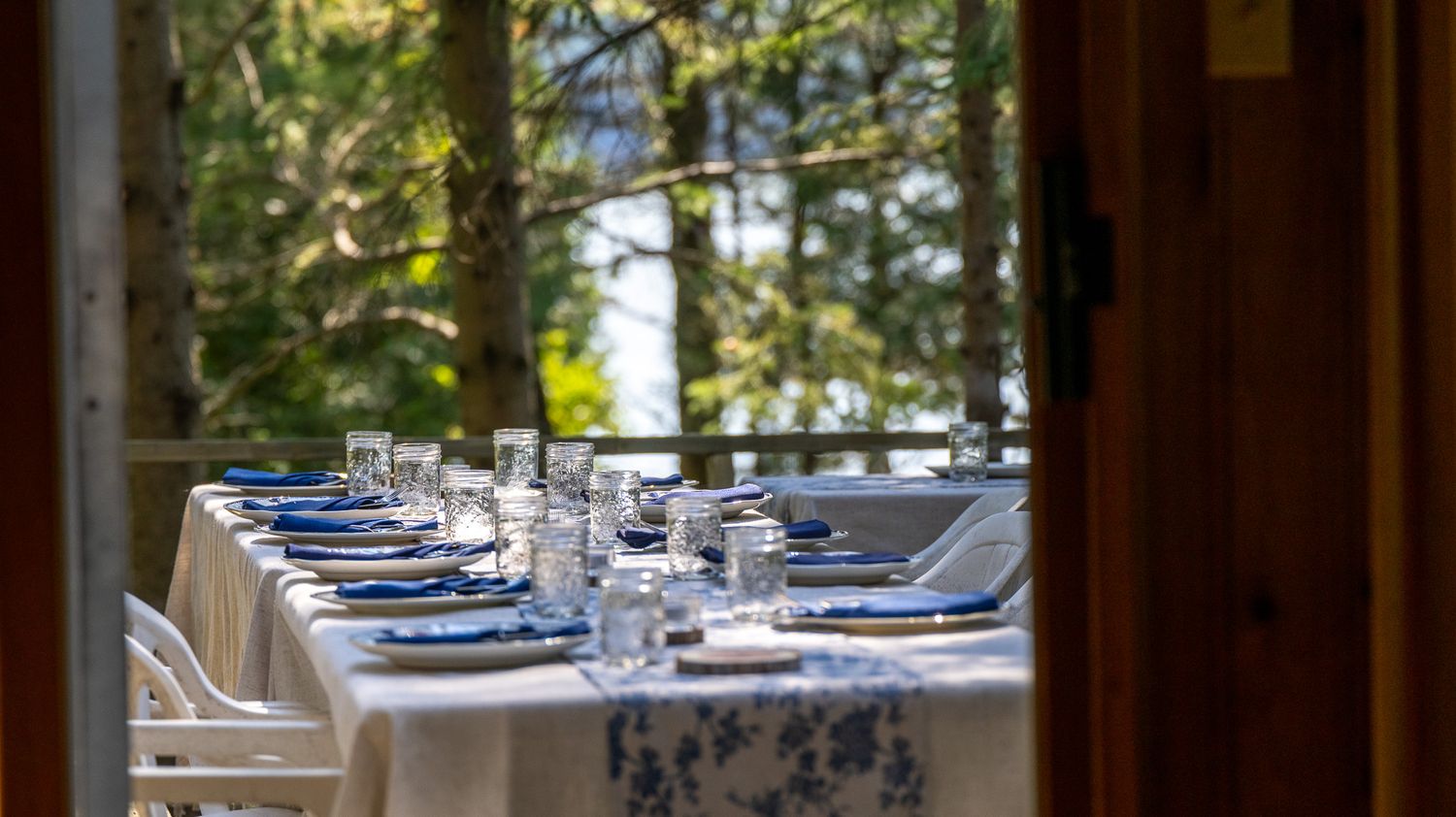 Elegant table setting with blue accents and glassware overlooking natural scenery.