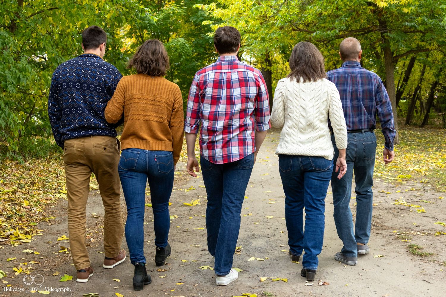 Group walking away on autumn path through wooded area.
