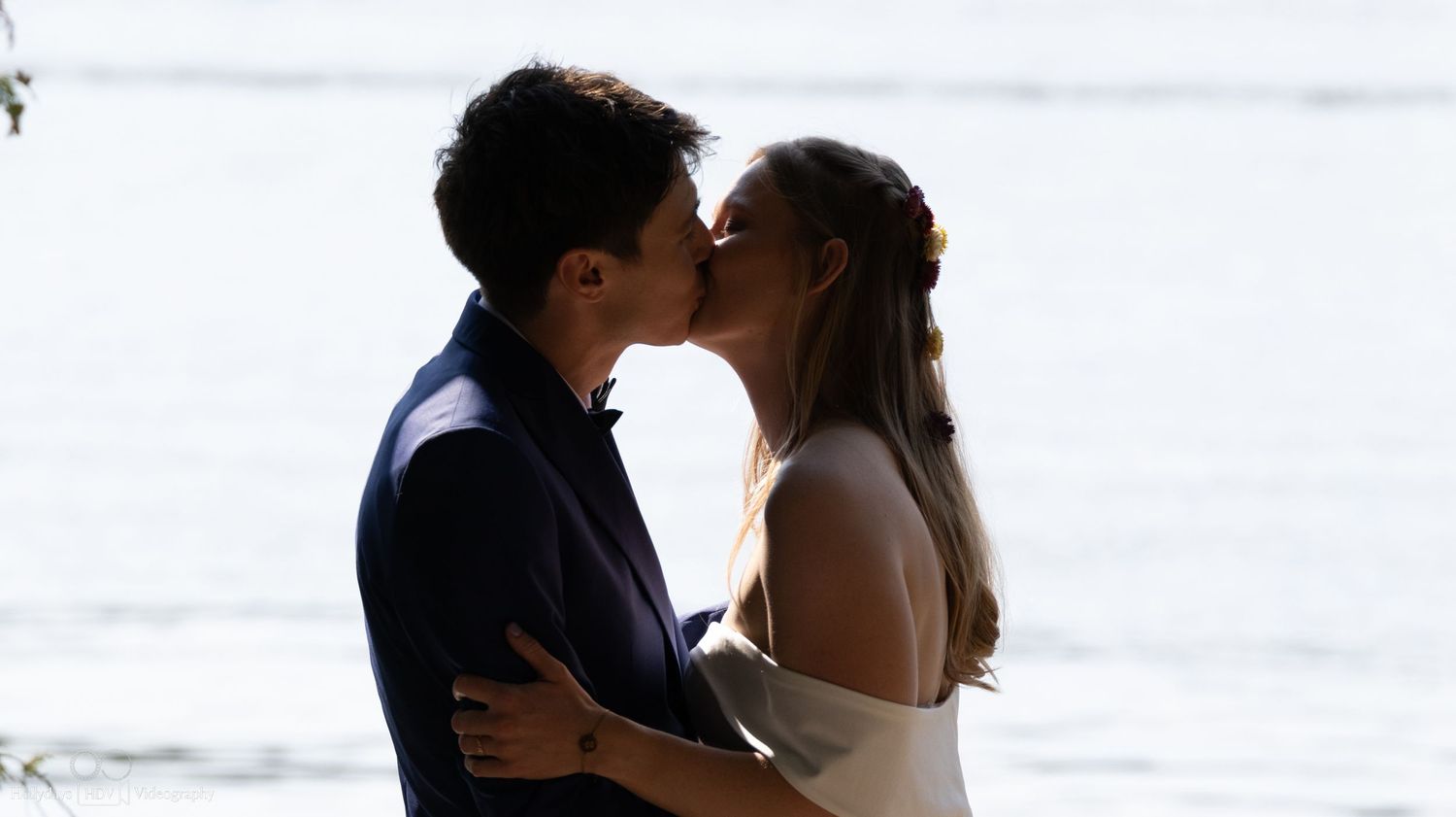 A silhouetted couple shares an intimate kiss during their waterfront wedding ceremony.