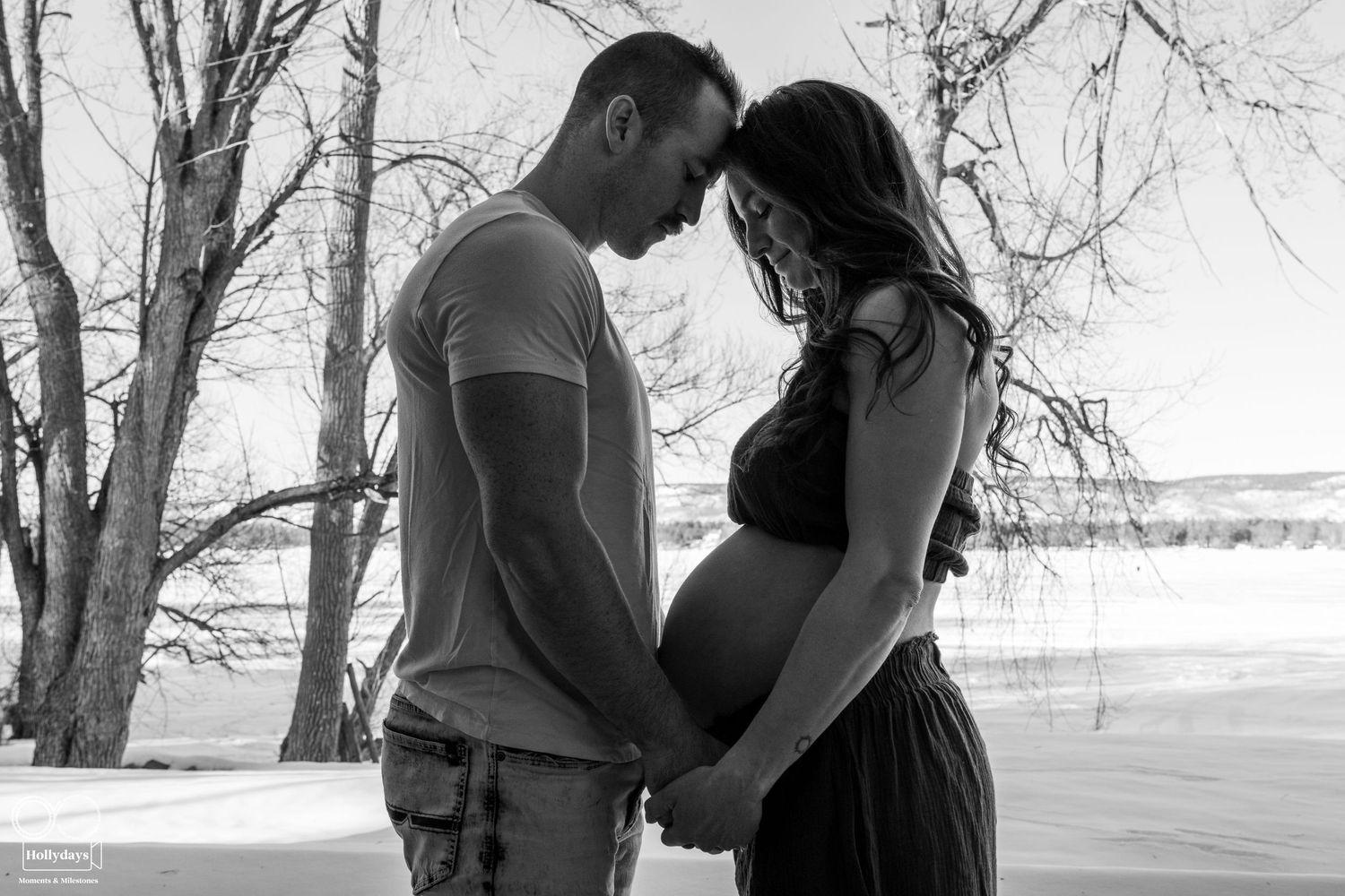 Black and white photograph of an intimate moment between a couple during a maternity photoshoot outdoors. Maternity photography