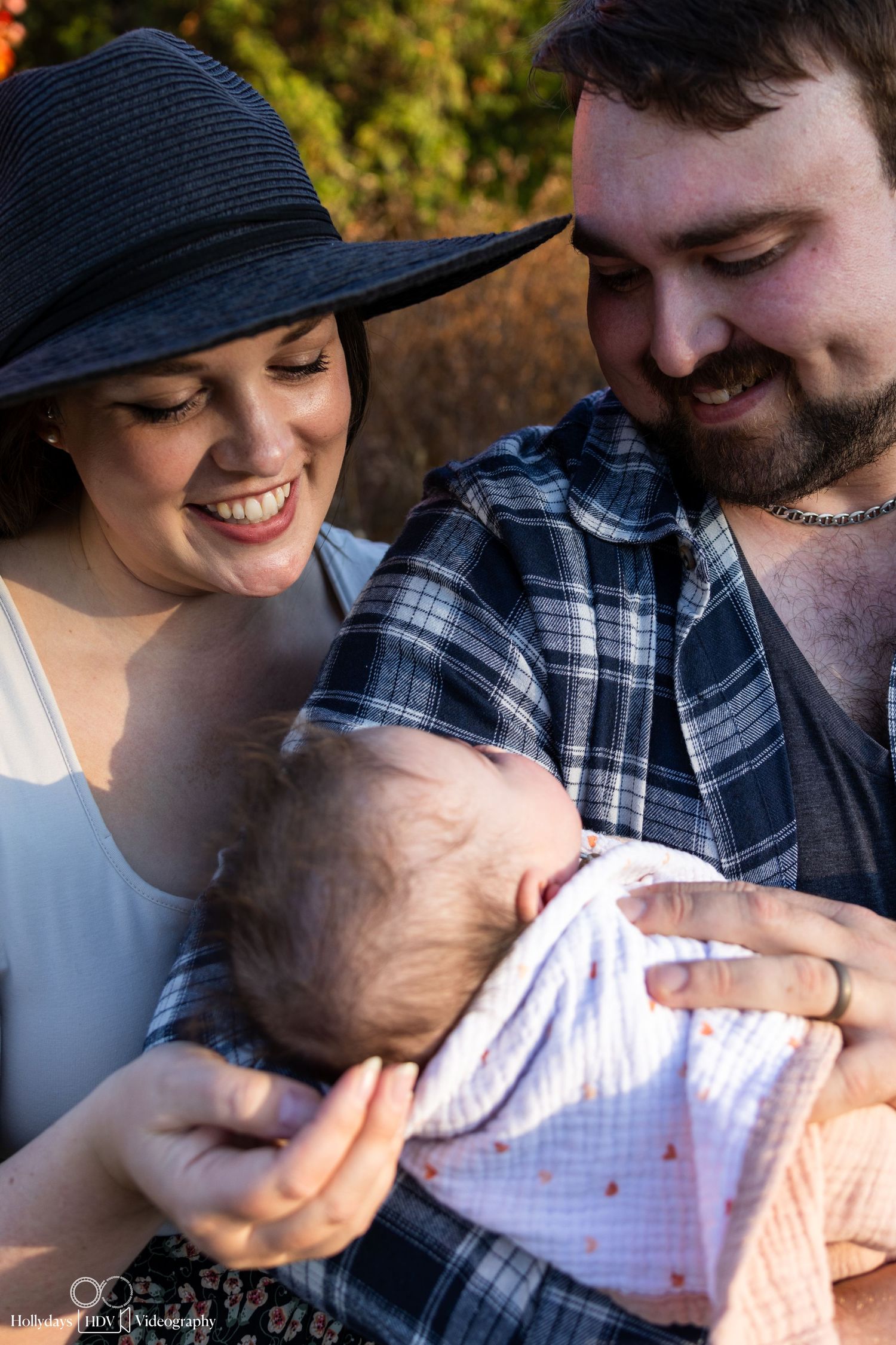 Intimate family moment with new baby outdoors on sunny day.