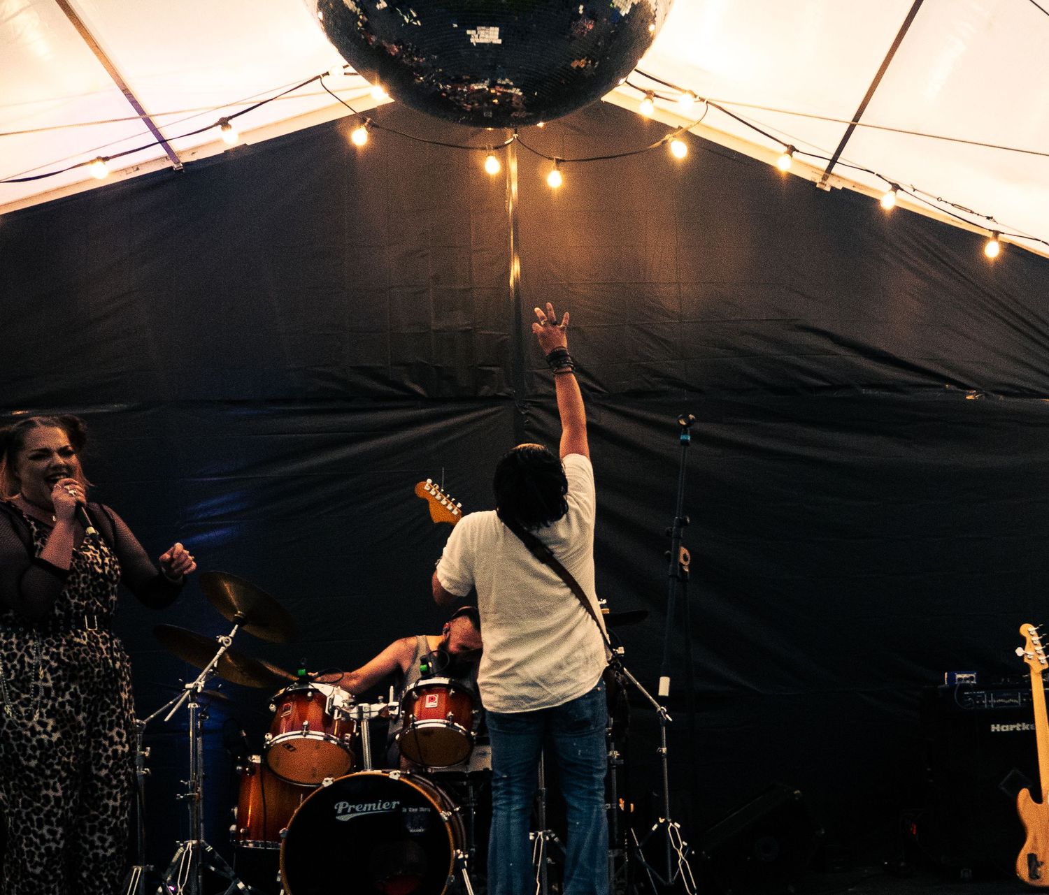 Musicians performing on stage with dramatic lighting and raised hands during an energetic concert.