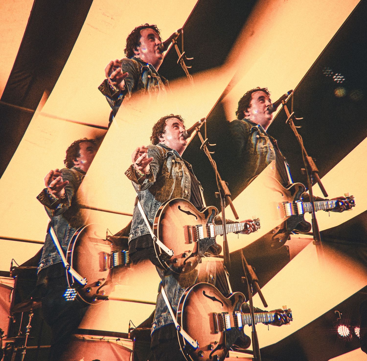Multiple exposure shot of a guitarist performing on stage under dramatic golden yellow lighting.
