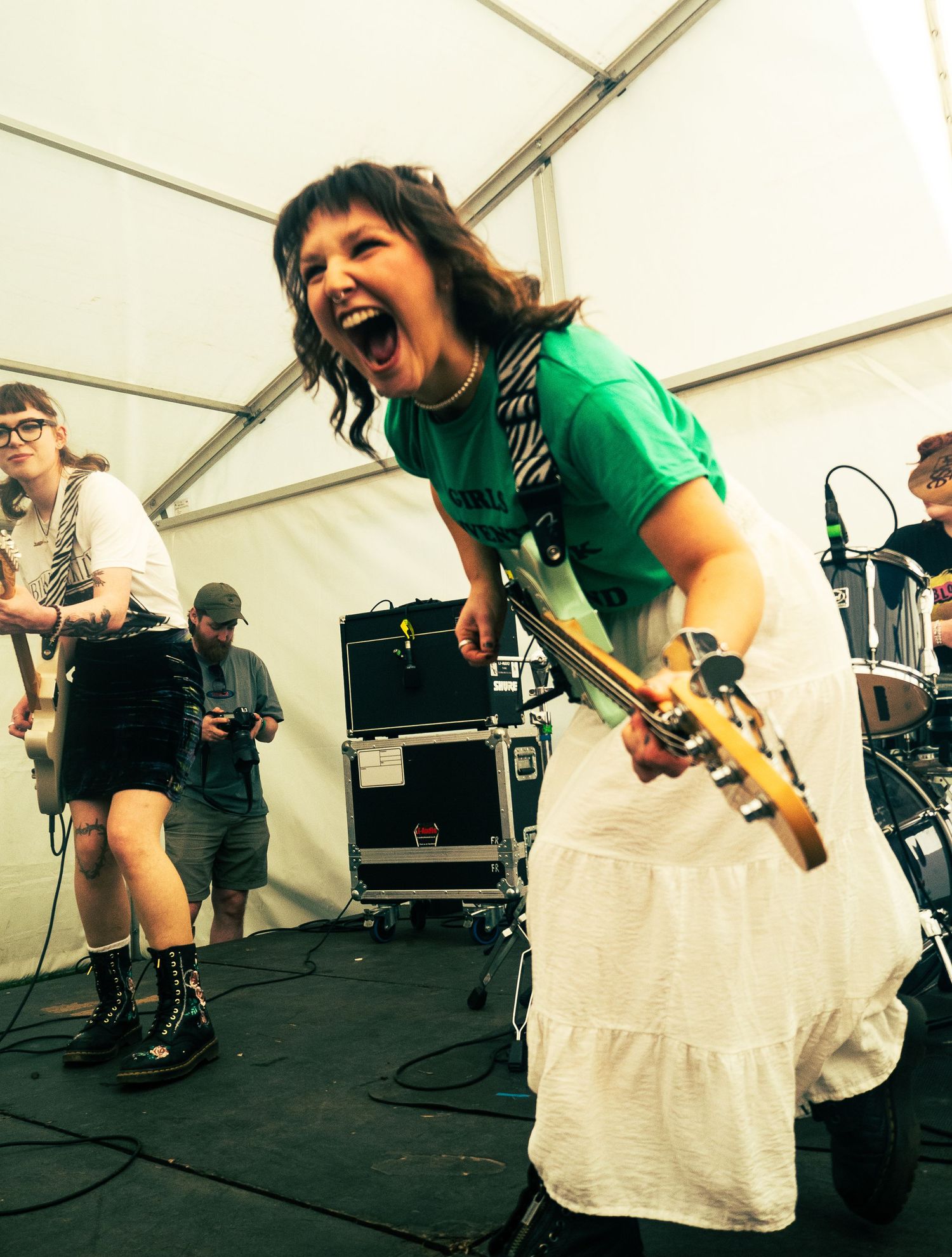Energetic performance by musicians with guitars on a stage under a white tent.