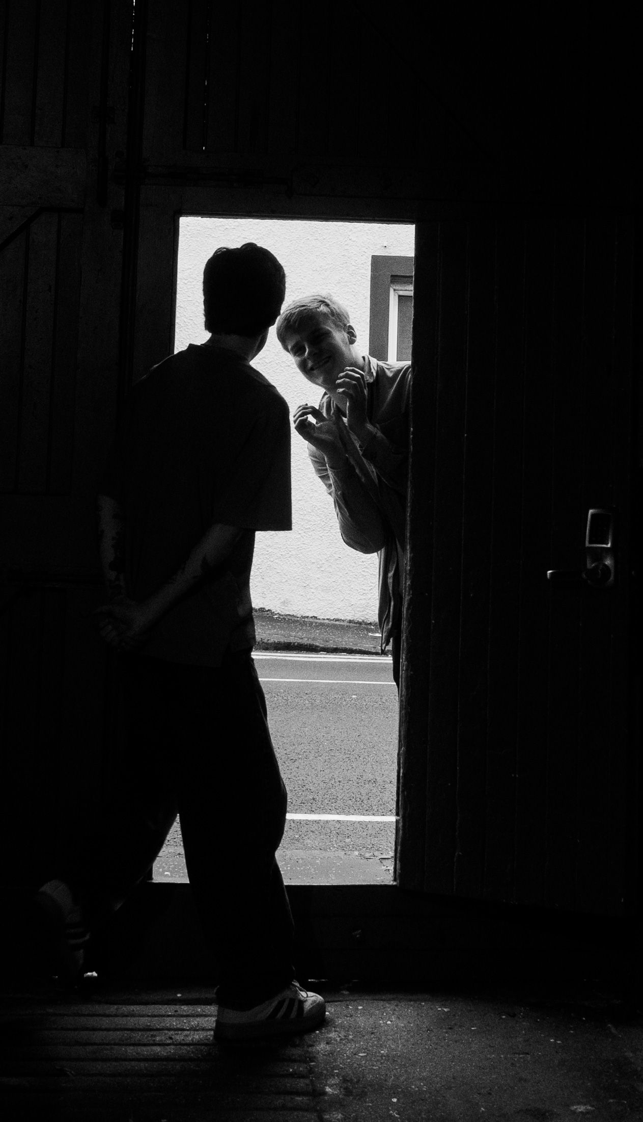 Silhouette of two people conversing in a dark doorway with bright light streaming from outside.