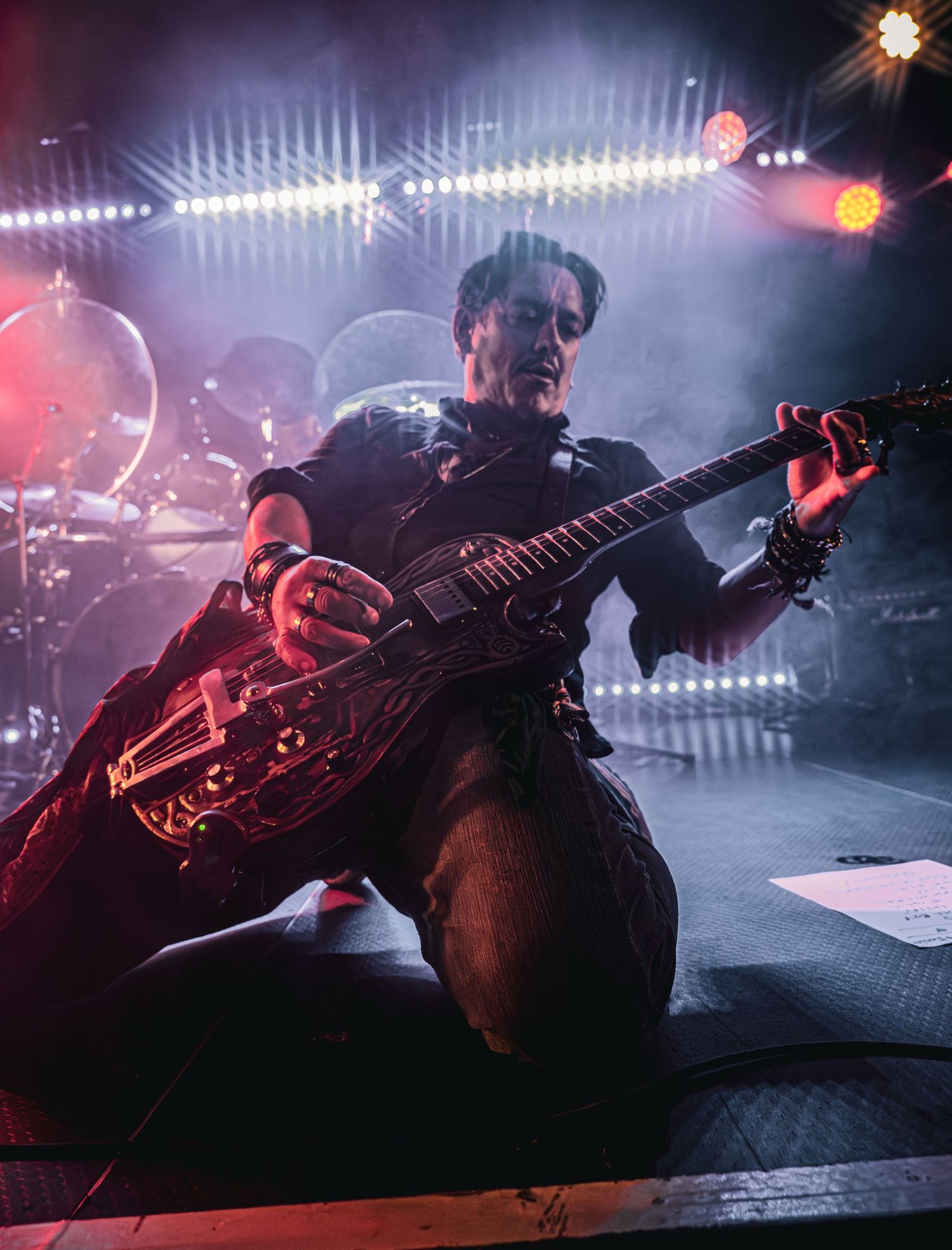Electric guitarist performs on stage under dramatic red and blue lights during a rock concert.