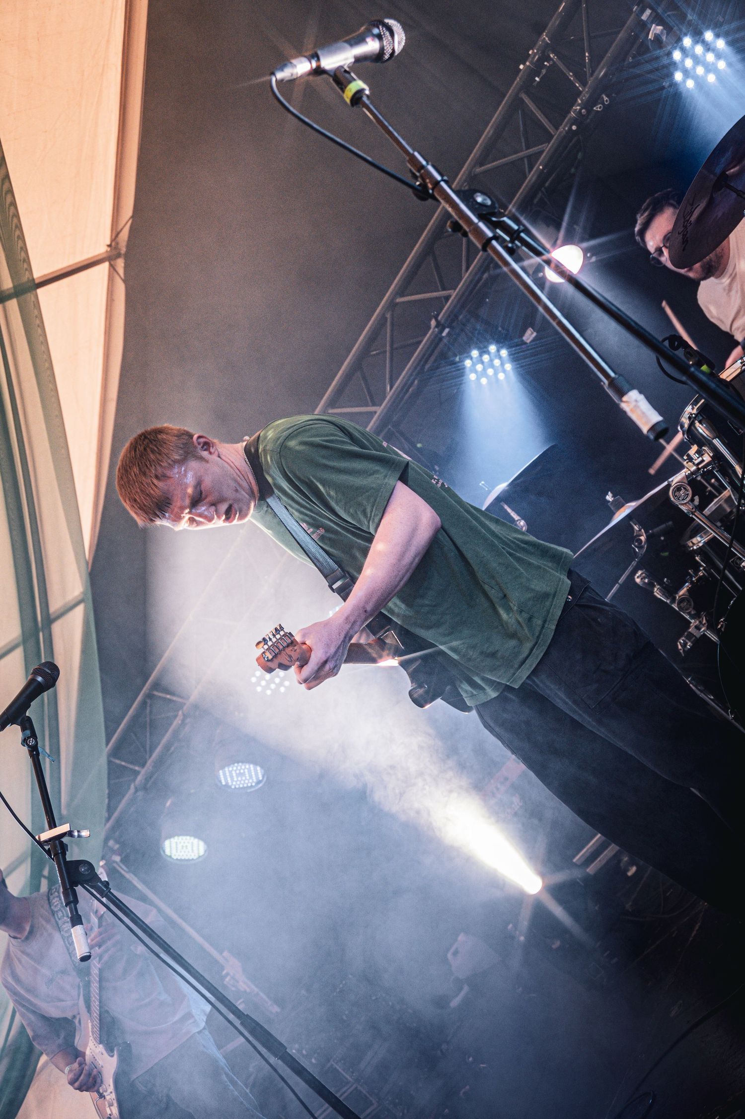 Overhead view of red-haired guitarist performing on illuminated stage with fog effects.