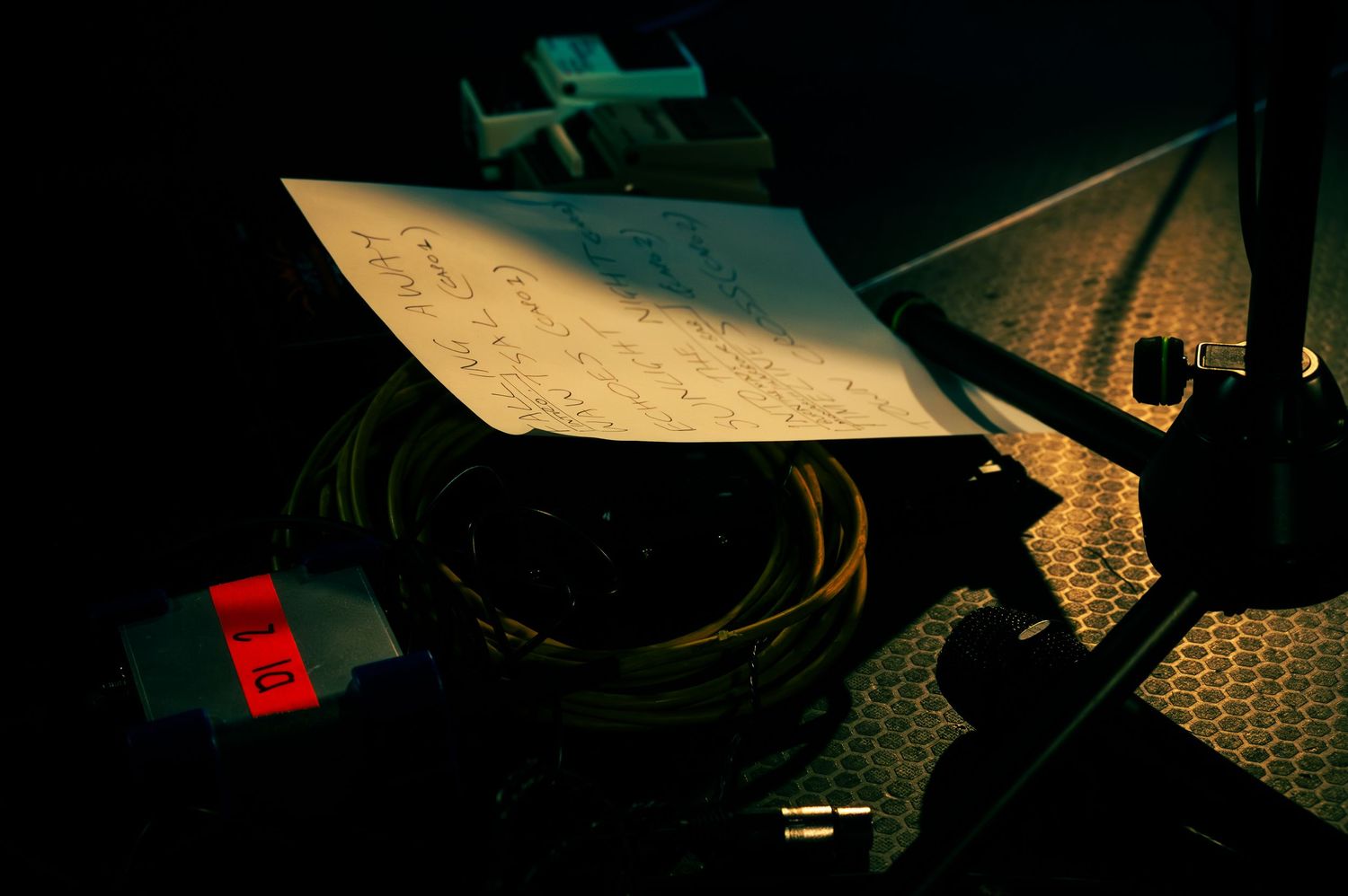 Papers and documents scattered across a dark surface create an atmospheric low-light composition.