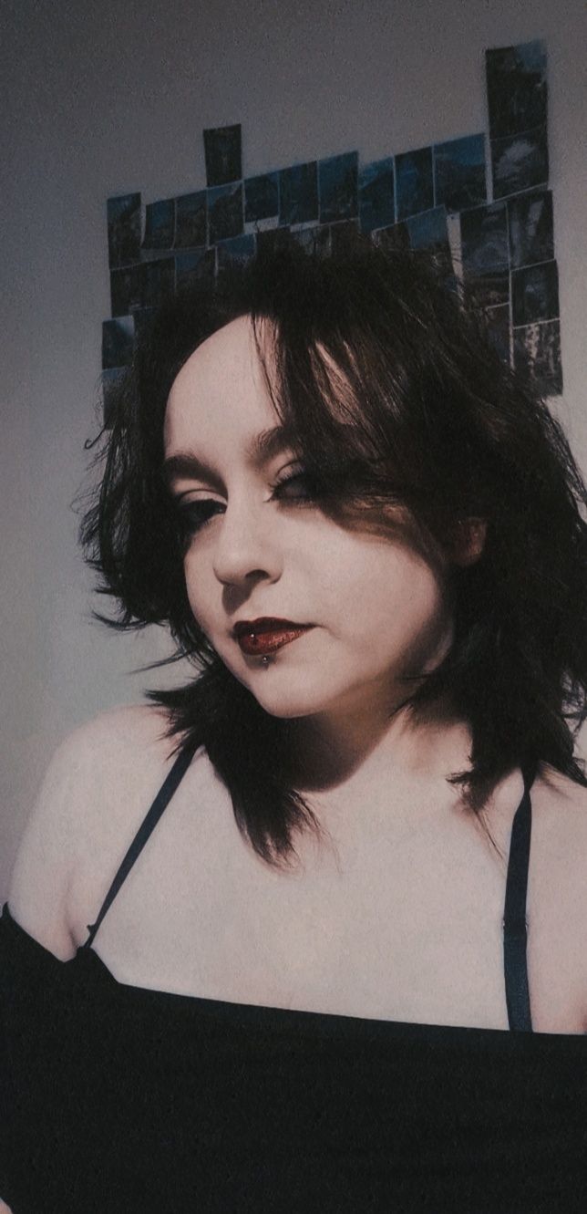 Portrait with gothic aesthetic featuring dark makeup and dramatic lighting.