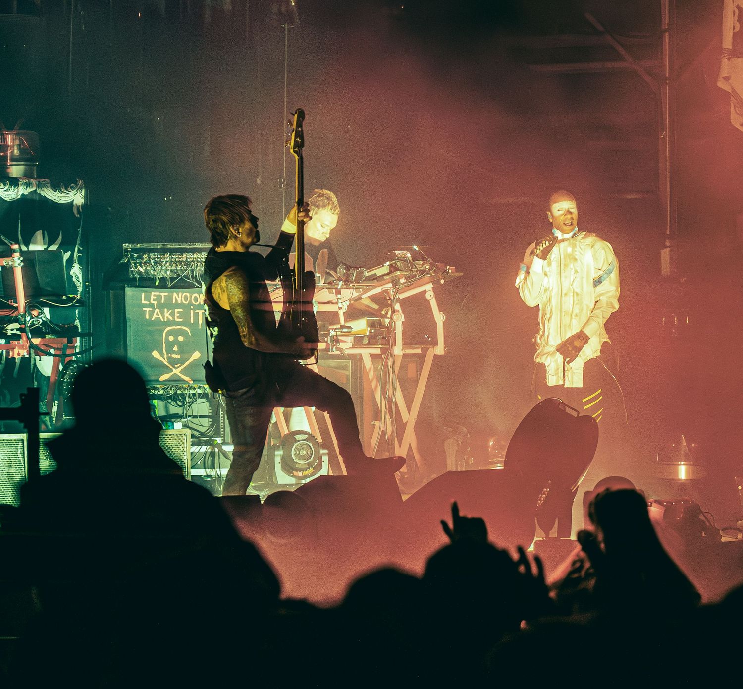 Rock band performing on stage with dramatic lighting, guitarist and vocalist in spotlight before a crowd.