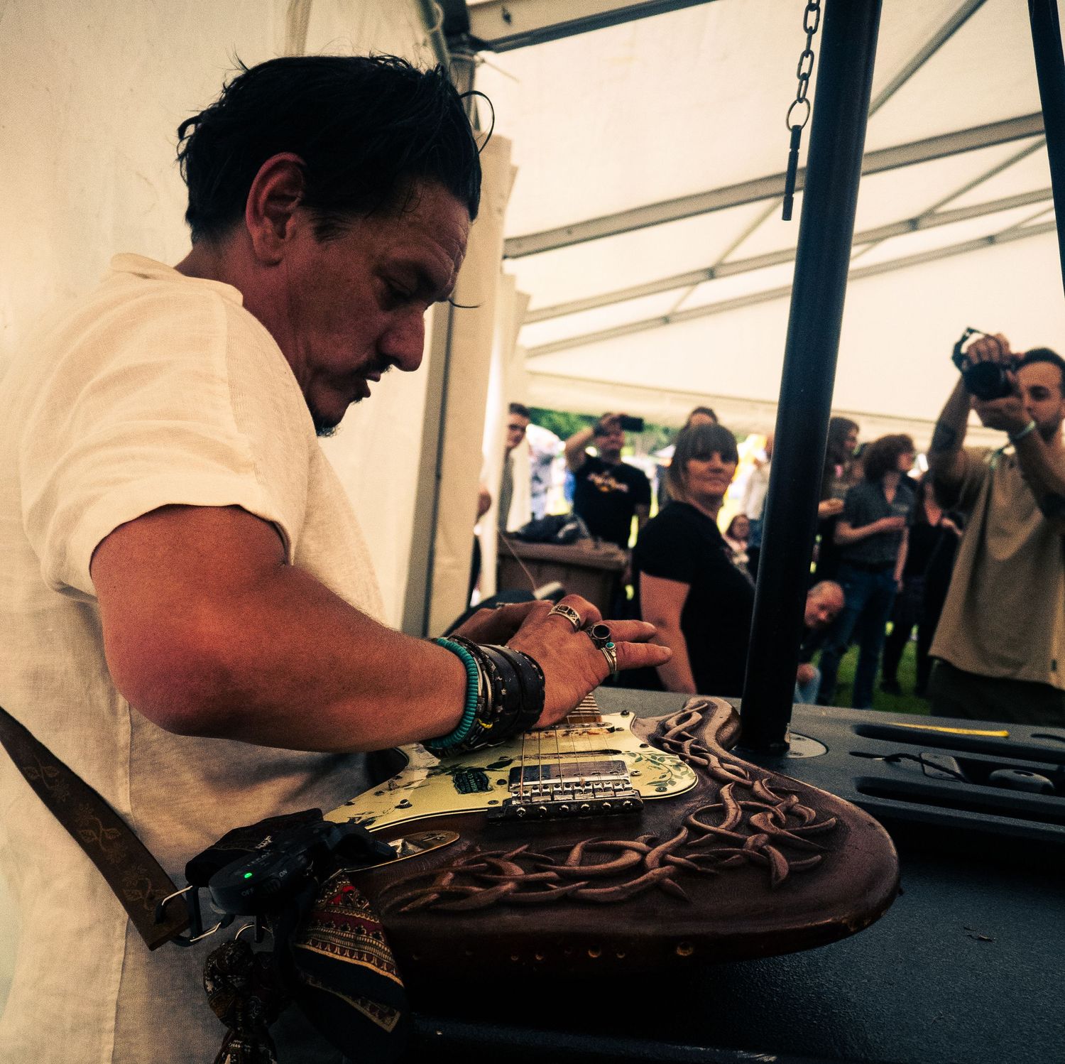 Musician signing an ornate instrument backstage at a concert venue.