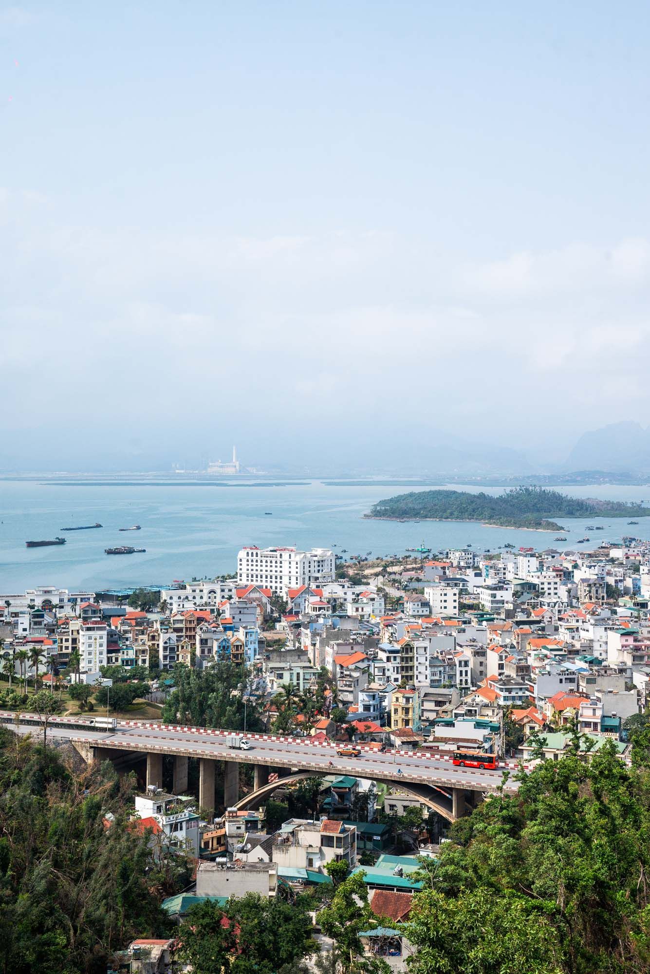 Panoramic cityscape view of Ha Long Bay city in Vietnam with modern buildings and mountains in the background.