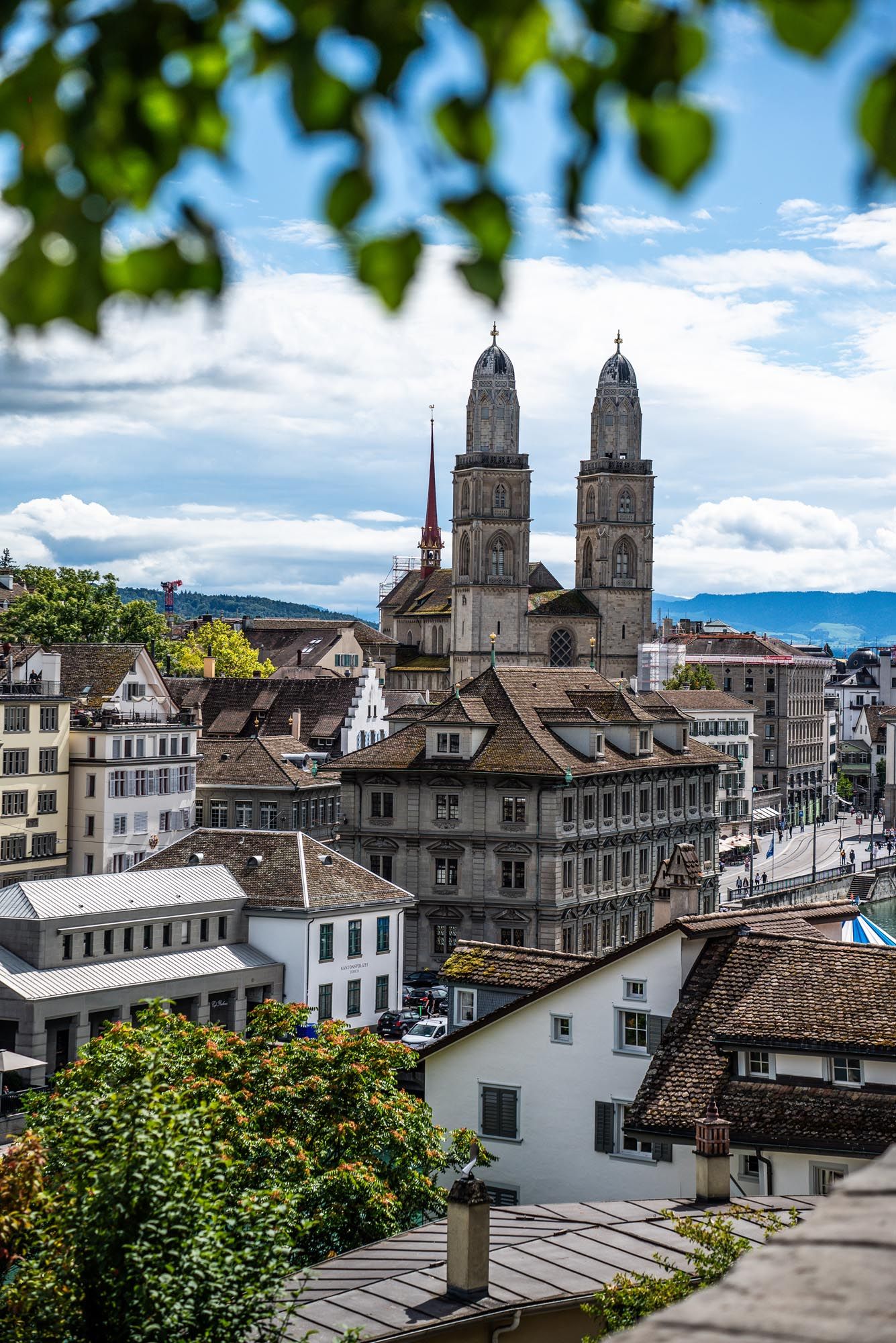 Panoramic cityscape view of historic Zurich with the iconic Grossmunster cathedral towers and traditional architecture.