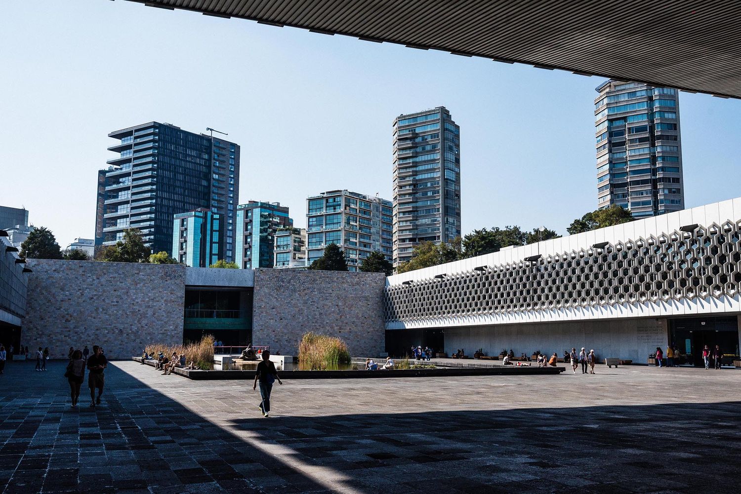 Modern urban architecture with glass skyscrapers and geometric buildings against a cloudy sky in a cityscape.