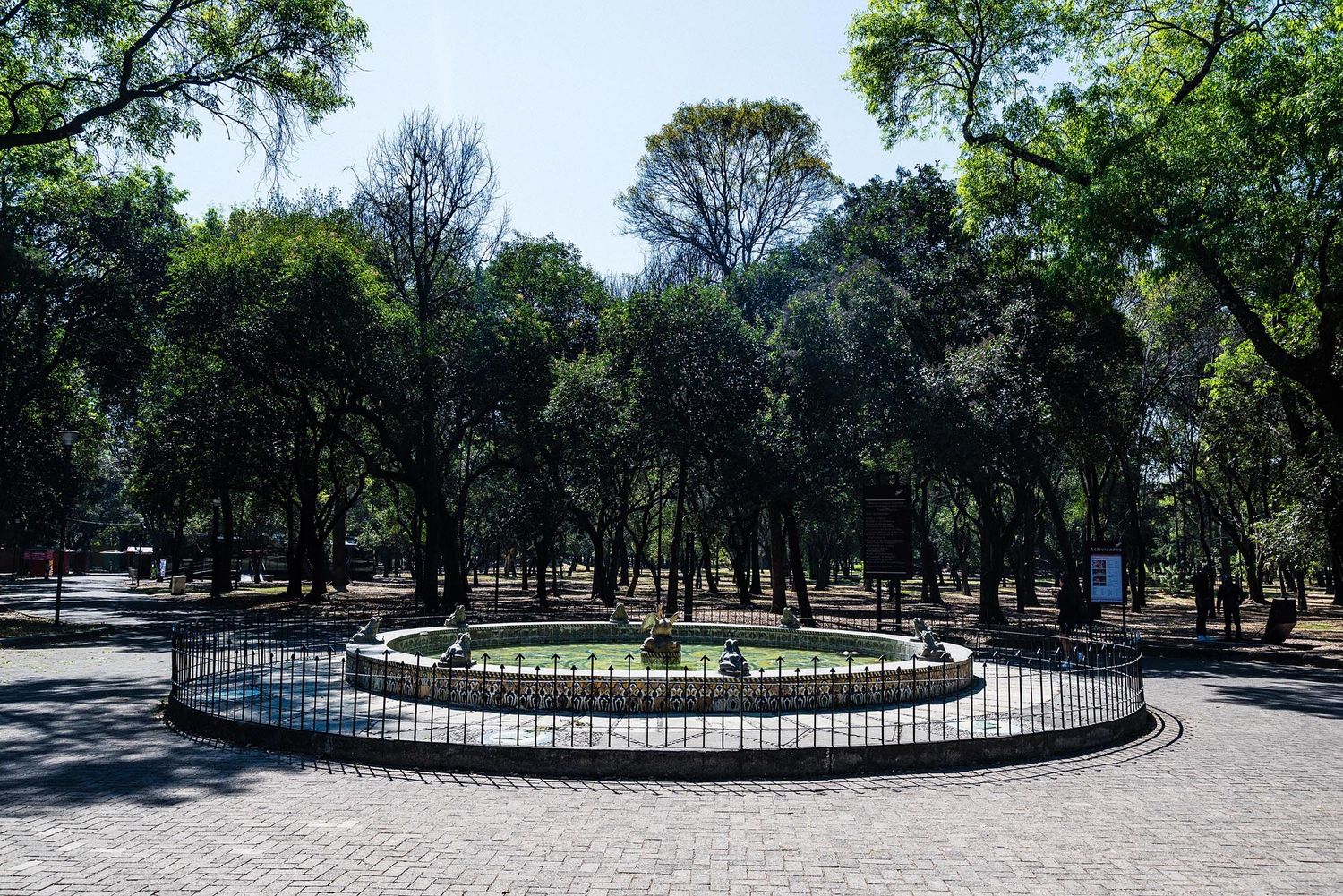 A panoramic view of a serene park pathway lined with mature trees and landscaped gardens.