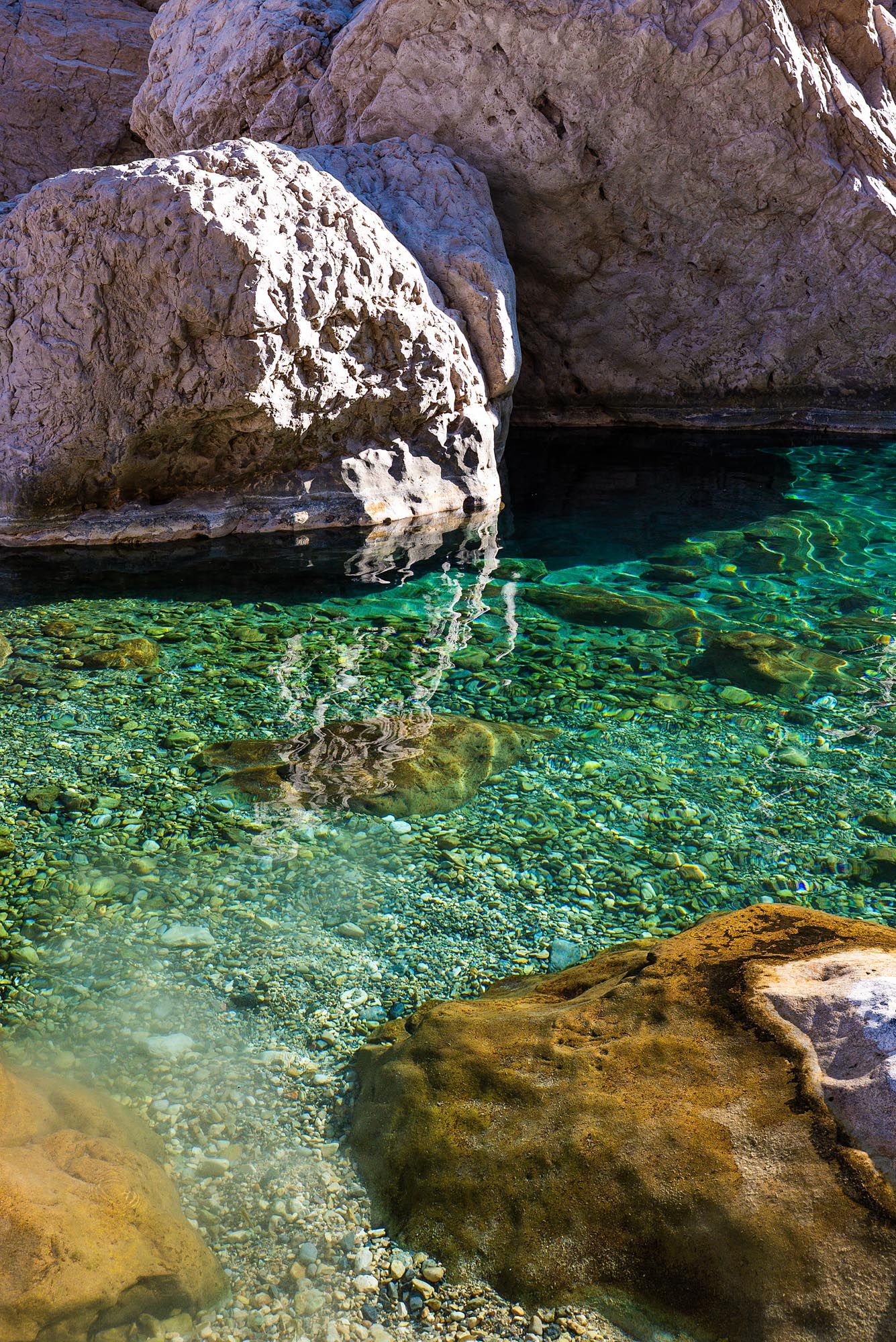 Crystal clear turquoise waters meet rocky limestone cliffs along a scenic Mediterranean coastline. Wadi Al Arbeieen