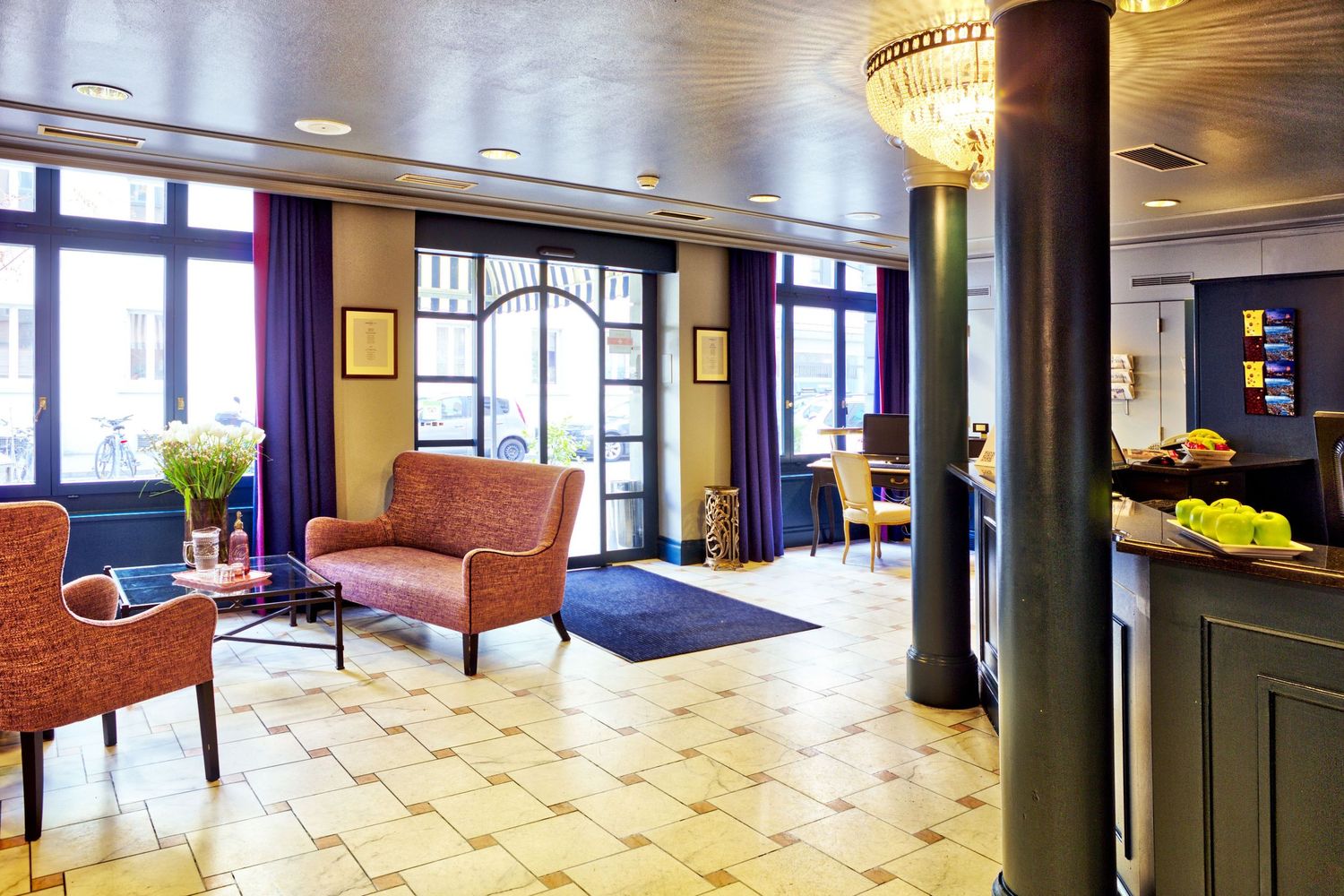 Modern office interior with black columns and tiled floors features sleek furniture and large windows for natural light.