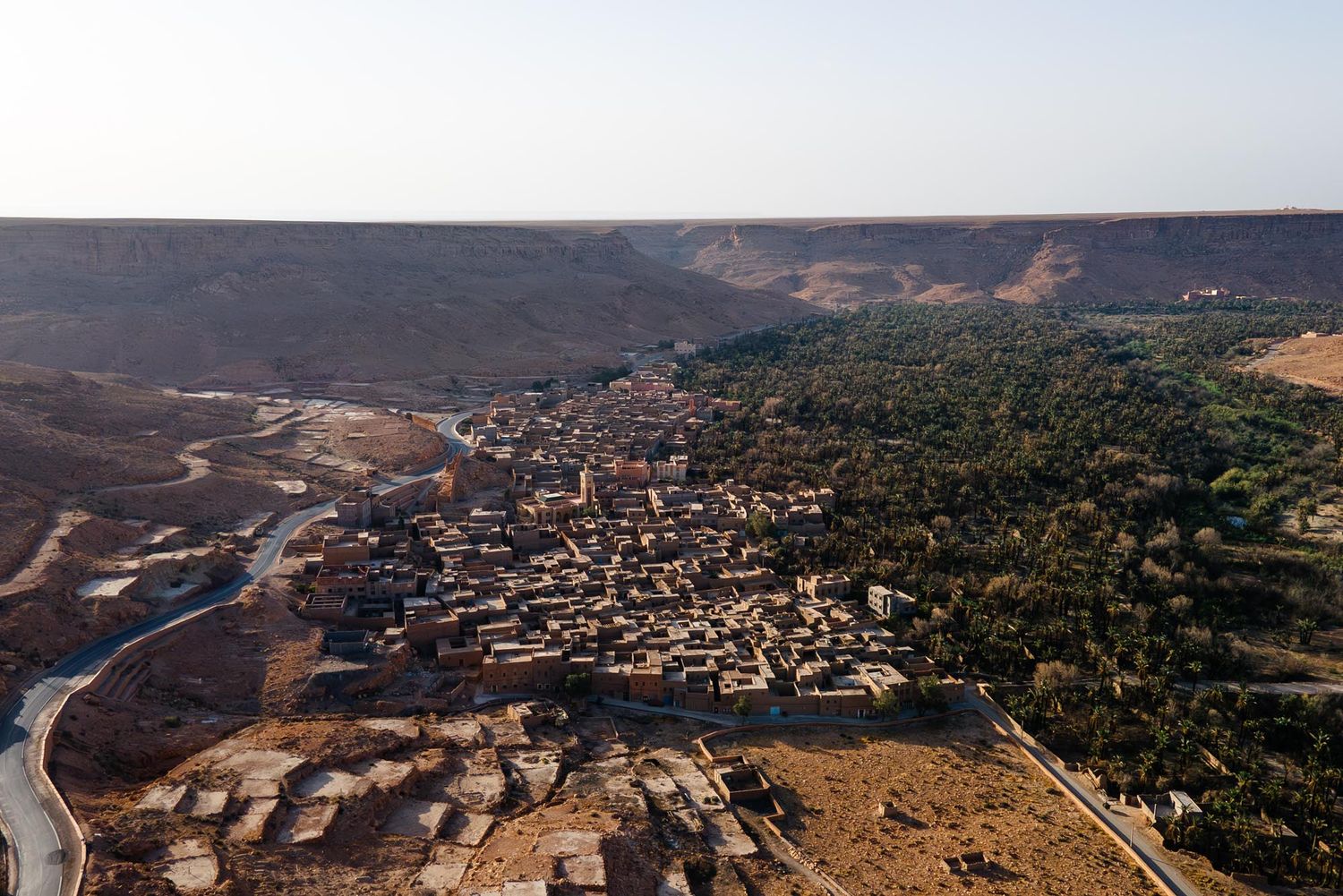Aerial panoramic view of a hillside residential development with homes and winding roads in a desert landscape.