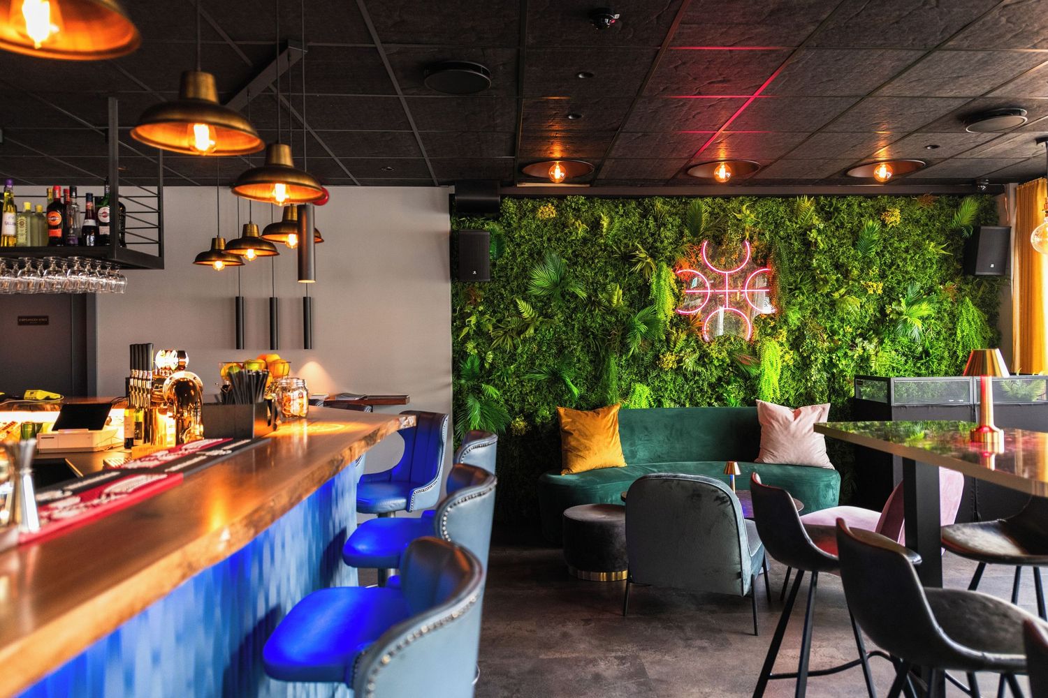 Modern restaurant interior with blue LED lighting along bar counter and pendant lamps hanging from dark ceiling.