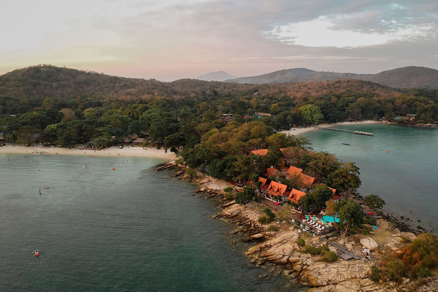 Aerial panoramic view of a coastal landscape with rocky shores, turquoise waters and lush green vegetation.