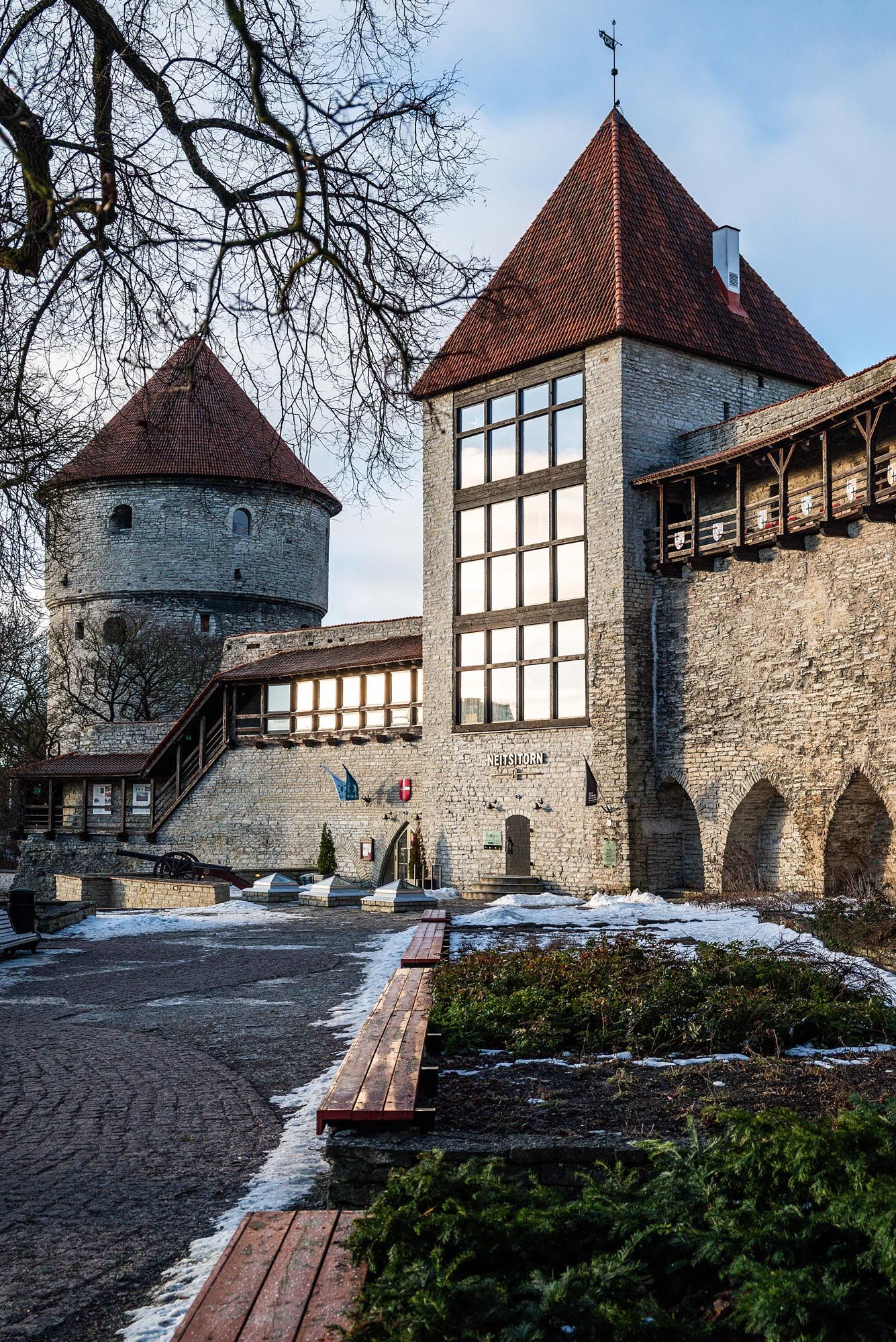 Medieval stone fortress with timber-framed buildings and towers along defensive walls covered in winter snow.