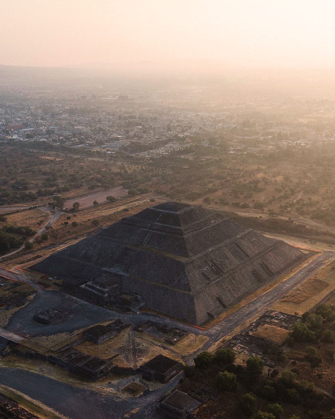 Aerial view of a large coal mining site with terraced excavation levels during sunset creating a dramatic industrial landscape.