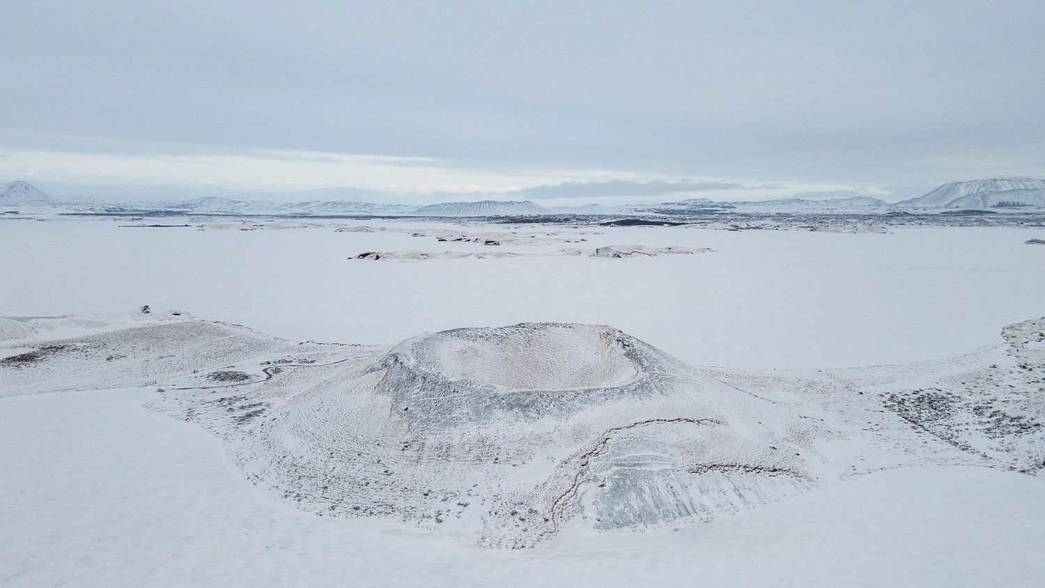 Aerial view of snow-covered mountain peaks and valleys in a remote winter landscape.