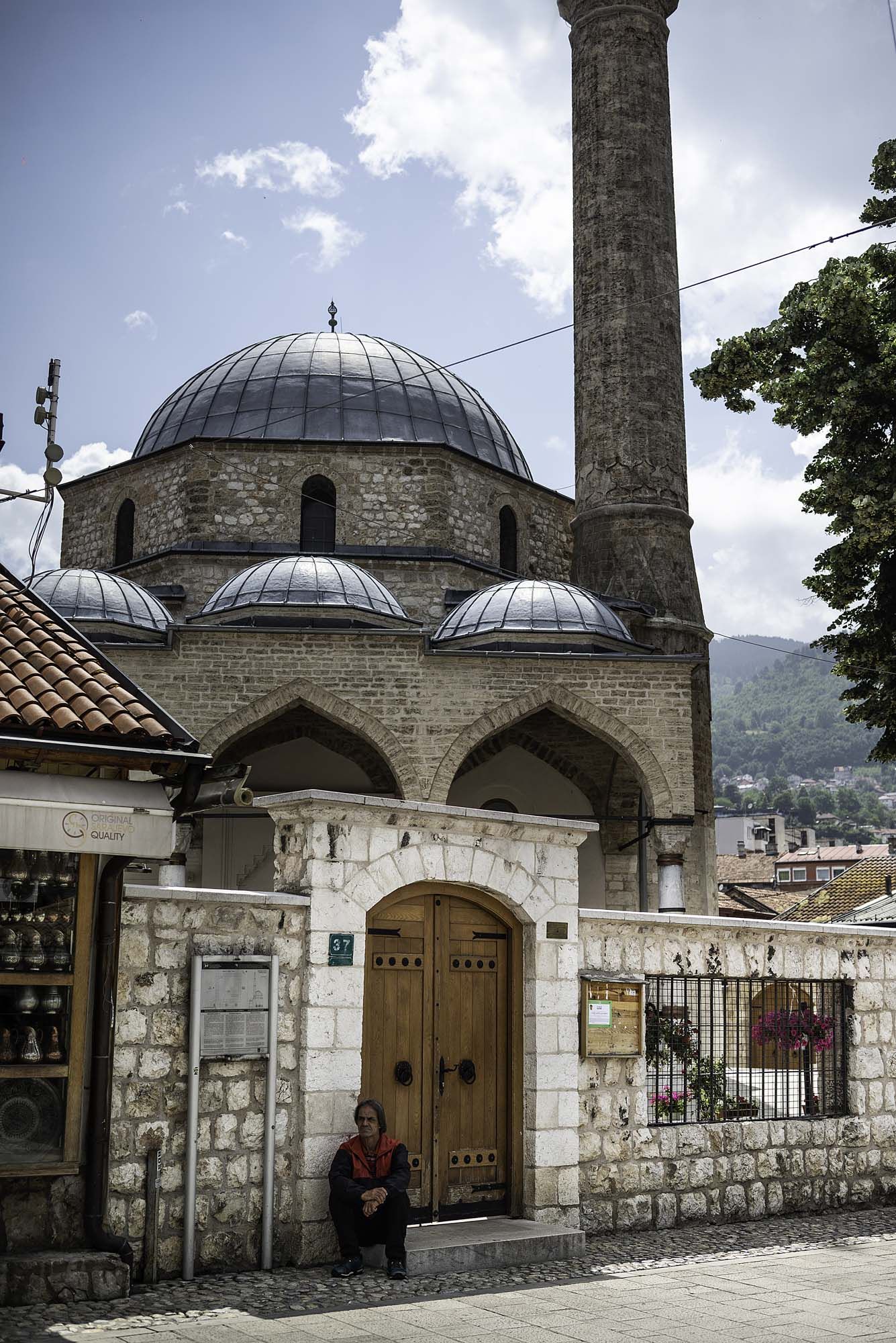 Historic mosque with multiple domed roofs and stone walls in Sarajevo's old town showcases traditional Islamic architecture.