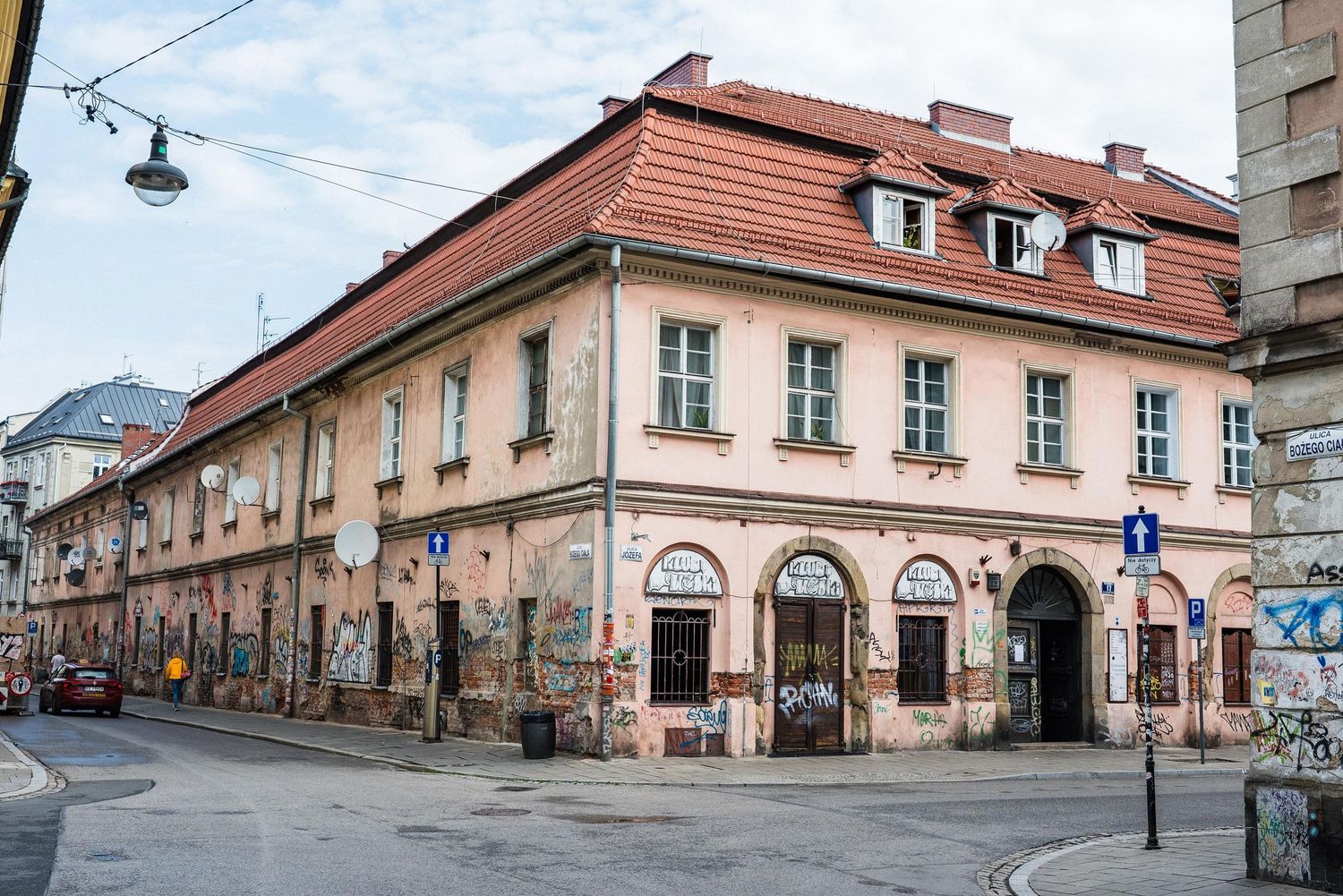 Historic corner building with terracotta roof and arched windows in Krakow's urban streetscape.