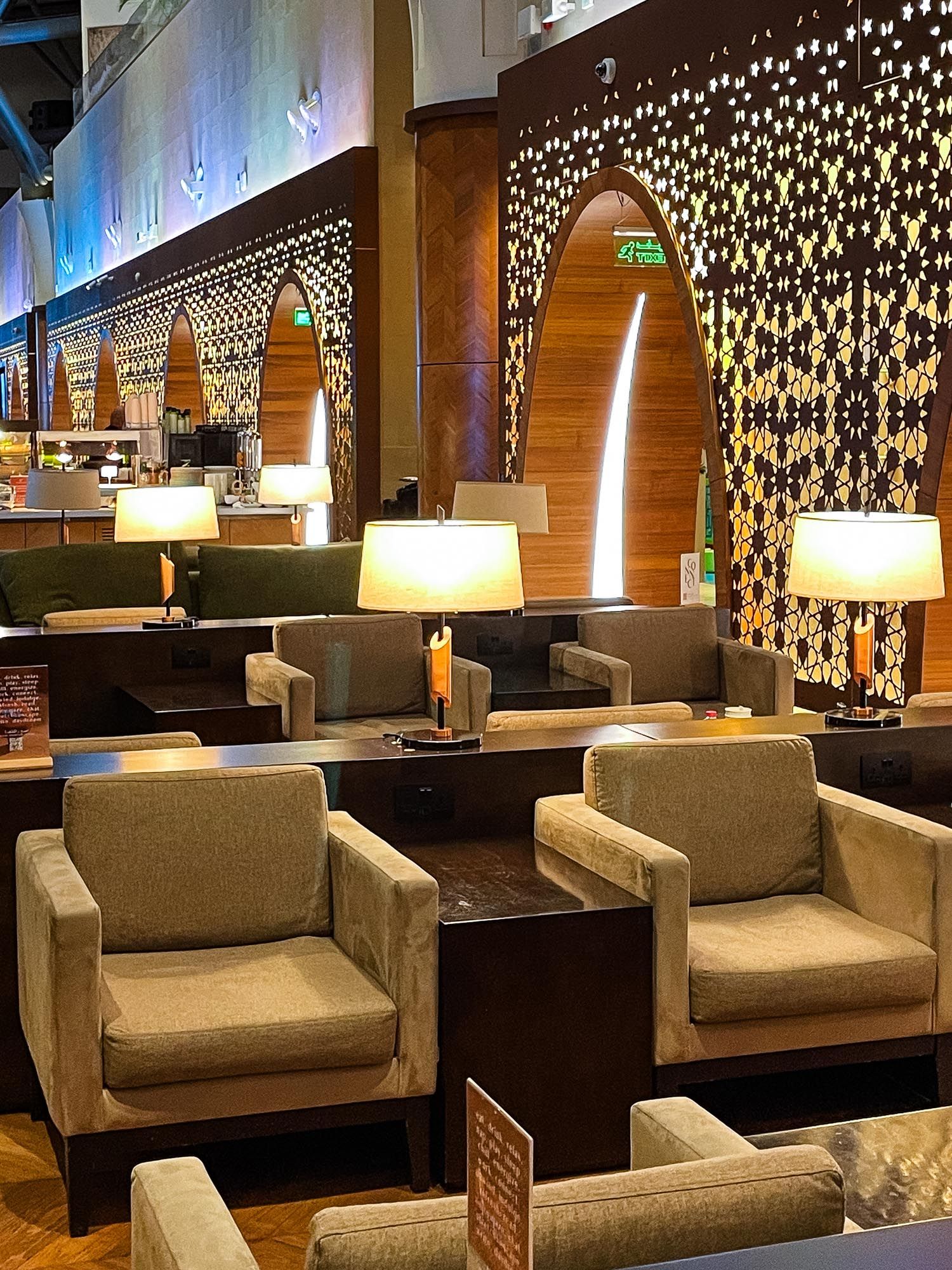 Modern lounge area with beige armchairs and decorative star-patterned lighting on dark walls creating an elegant ambiance.