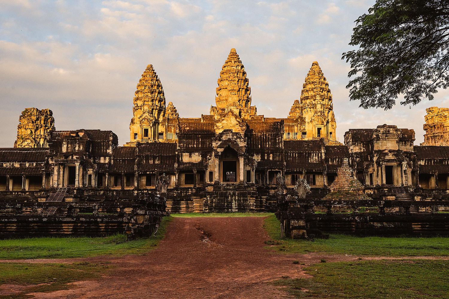 Panoramic view of Angkor Wat temple complex at sunset showing ancient stone towers and structures in Cambodia.