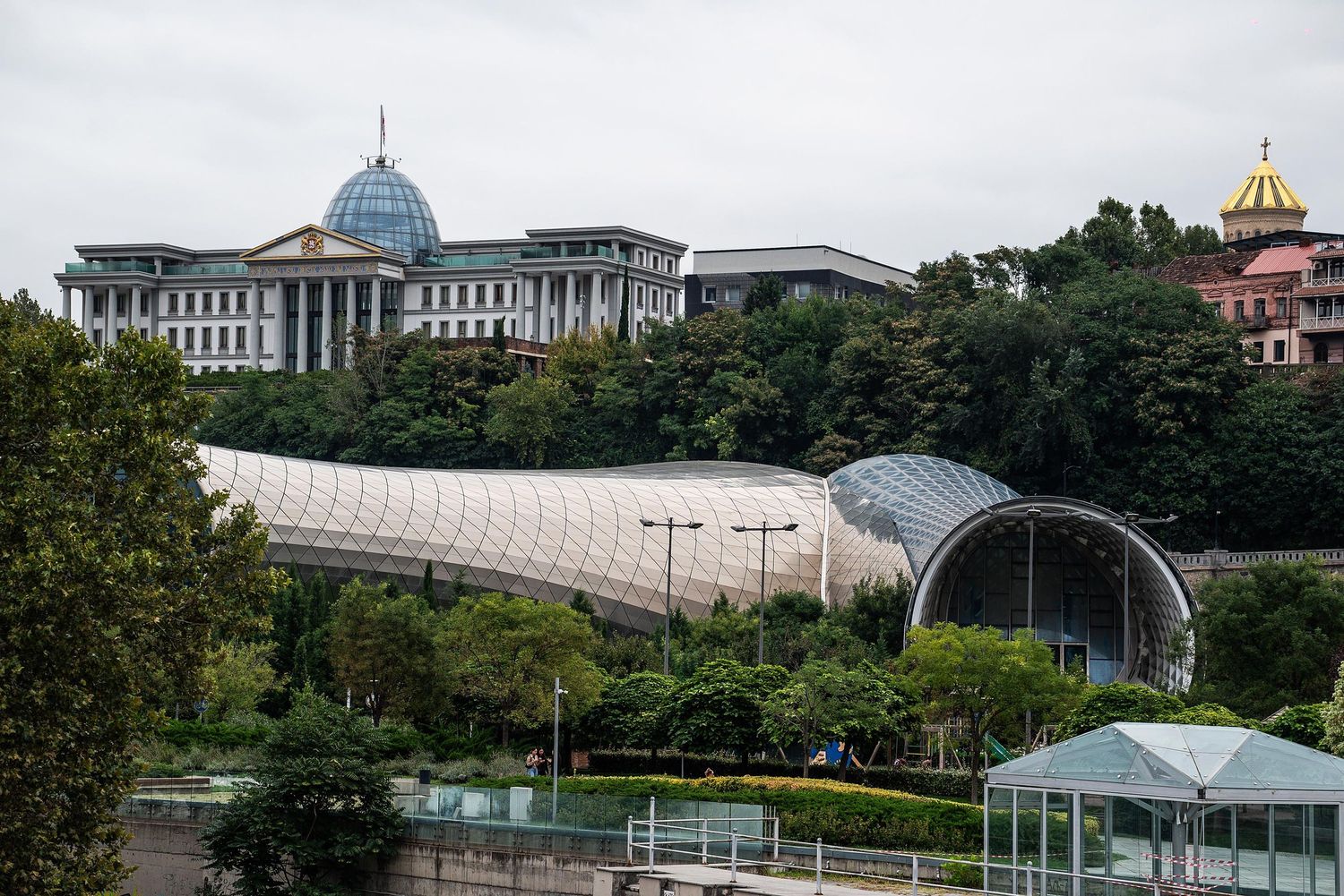 Panoramic view of multiple modern buildings and structures in an urban setting with domed roofs and glass architecture.