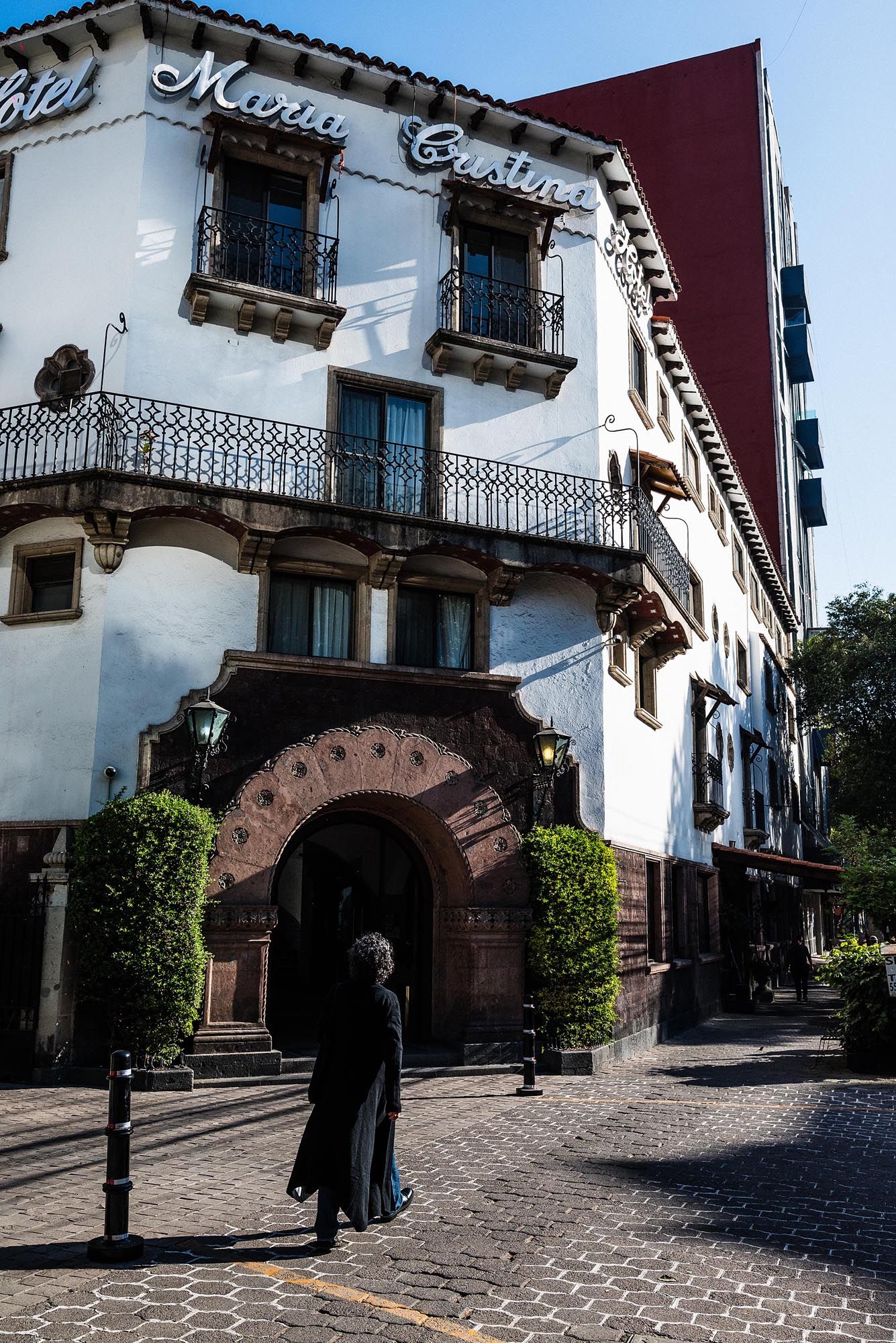 Architectural details of white Spanish colonial buildings with arched doorways and cobblestone streets in Mexico.