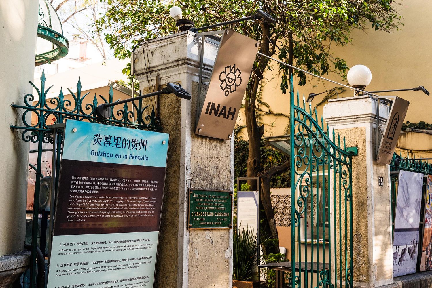 Historic wrought iron gate and stone entrance with green foliage at a heritage building in Macau.