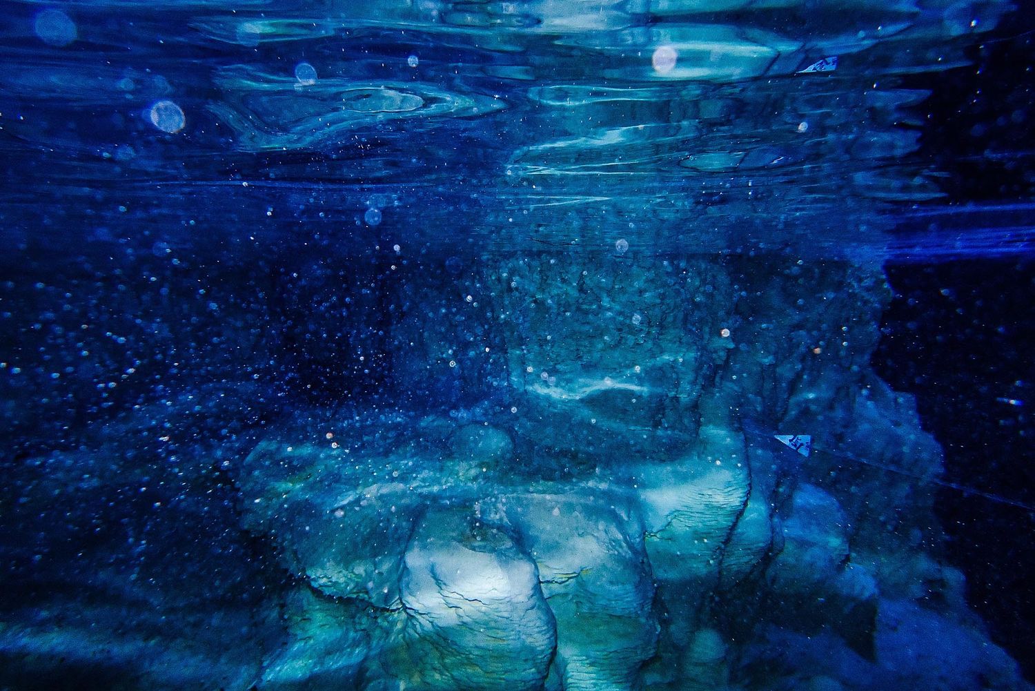 Underwater abstract scene with ethereal blue lighting and bubbles creating a dreamy aquatic atmosphere.